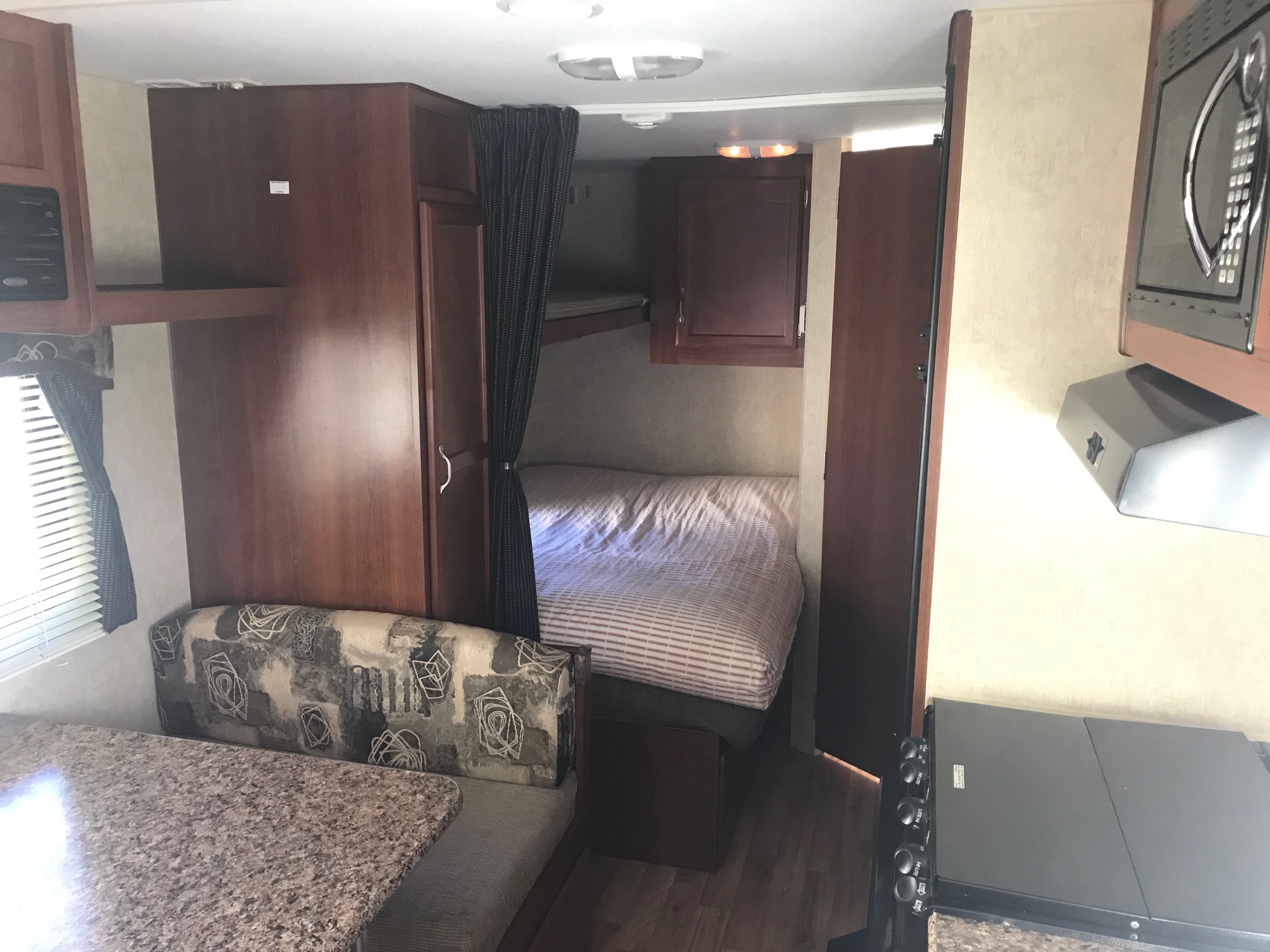 Cozy RV rental interior with dinette, bunk beds, and kitchen area, ideal for compact travel living.. Outdoors Rv Manufacturing Back Country 2011