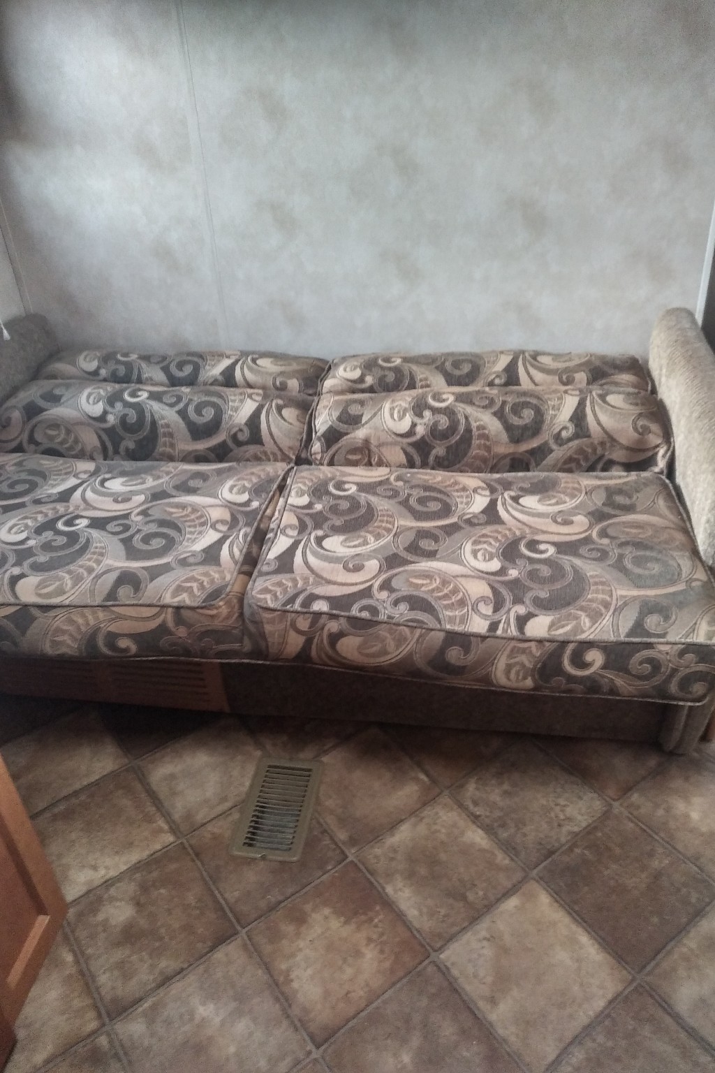This RV rental features a comfortable, patterned sofa with multiple cushions and a tiled floor with a vent, perfect for relaxing.. Palamino Puma 23FB 2013