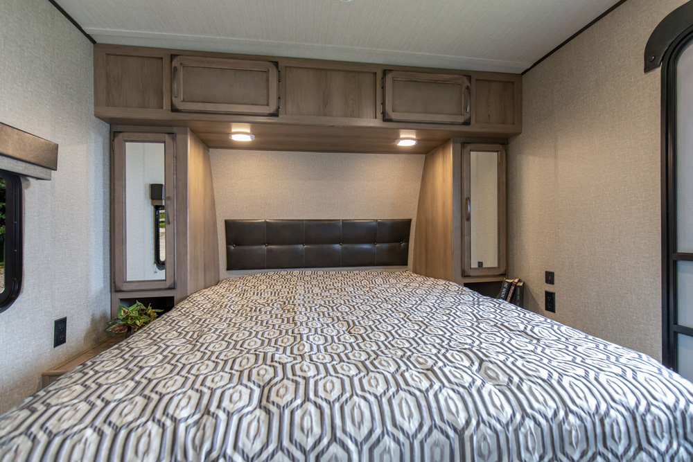 Cozy RV rental bedroom with a comfortable bed, ample overhead and side storage, and accent lighting for your travels.. Grand Design Transcend 2019