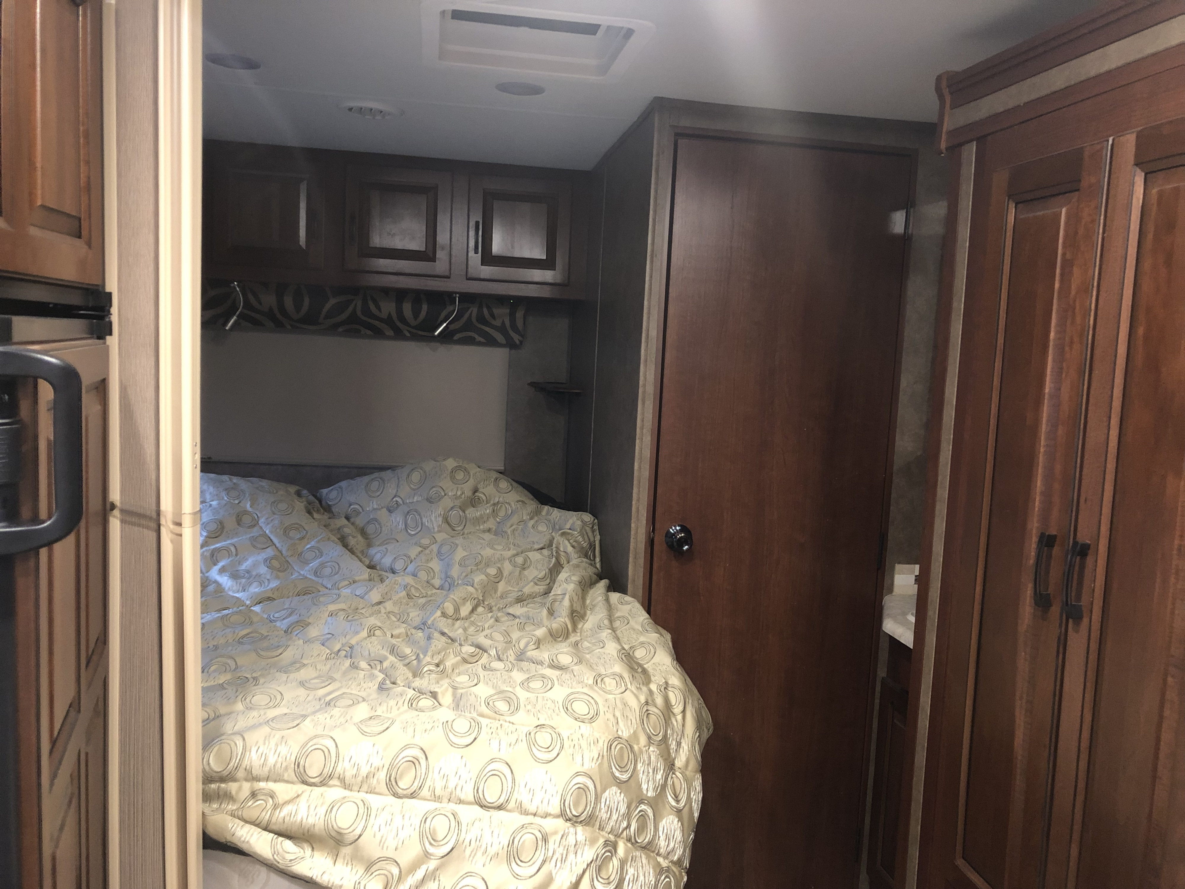 Cozy RV rental bedroom with patterned comforter, overhead cabinets, and compact design. Perfect for your next adventure.. Forest River Flagstaff 2017