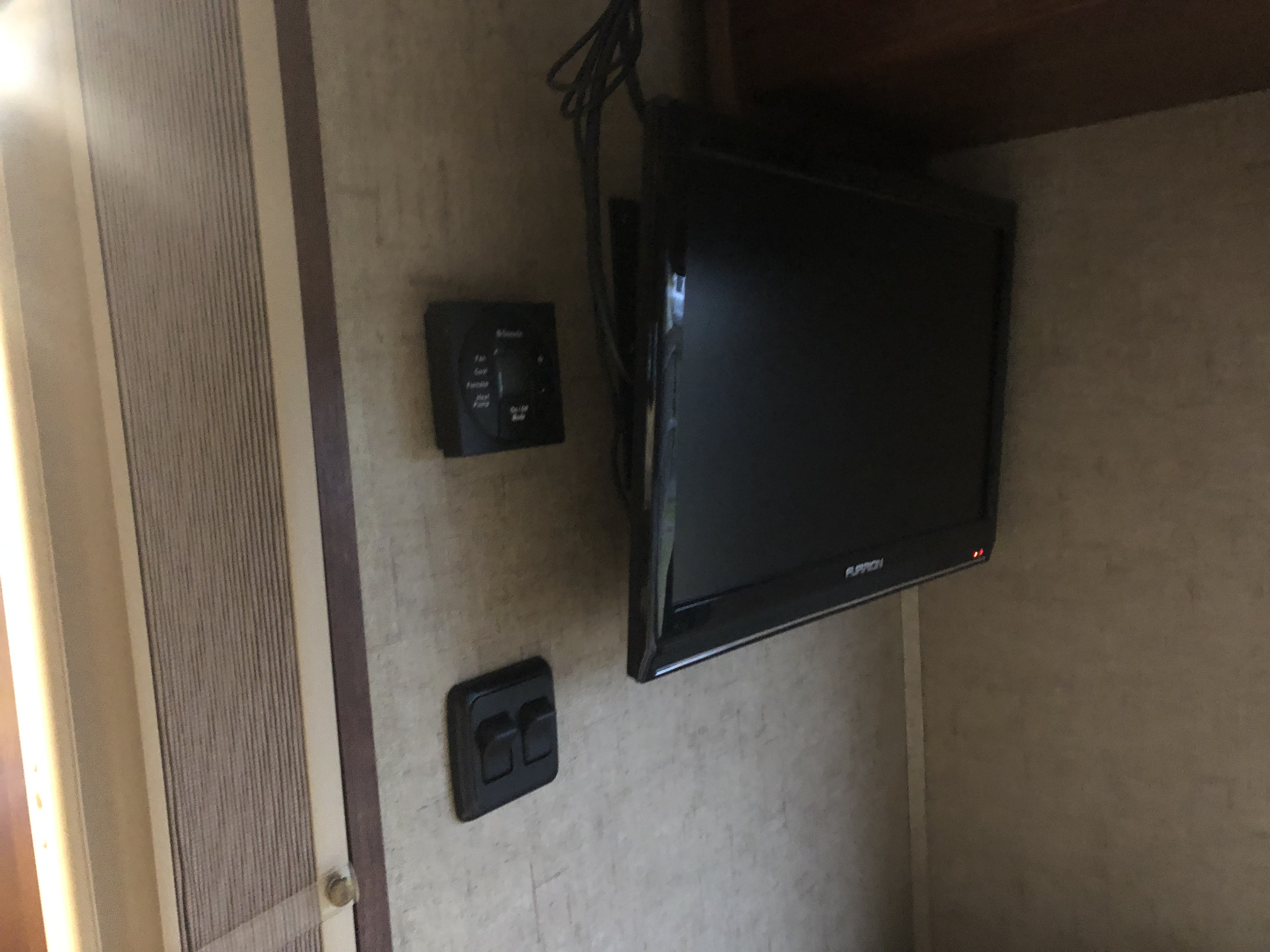Essential RV rental interior features: a mounted TV, Dometic thermostat, and light switches for a comfortable stay.. Forest River Flagstaff 2017