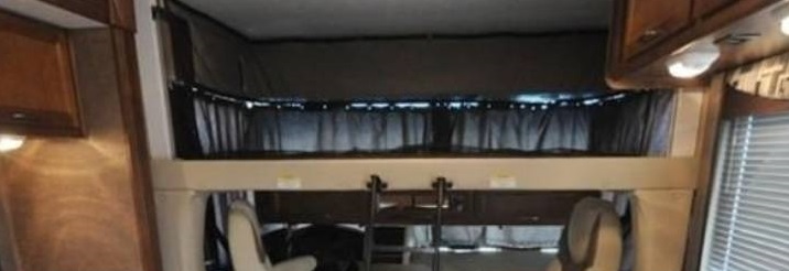 Interior of an RV rental: an overhead bunk bed with a ladder, providing compact sleeping and living space.. Coachmen Pursuit 2014