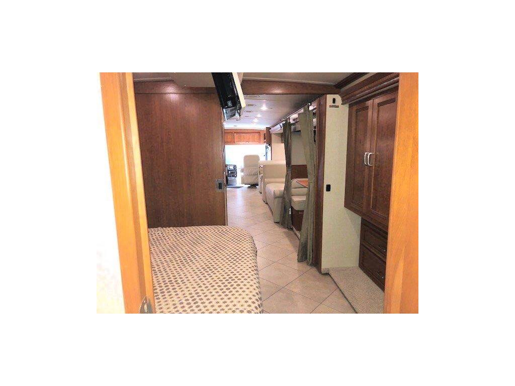 Inside a well-appointed RV rental, showing the living space with wood cabinetry, comfortable seating, and sleeping area.. Winnebago Forza 2014