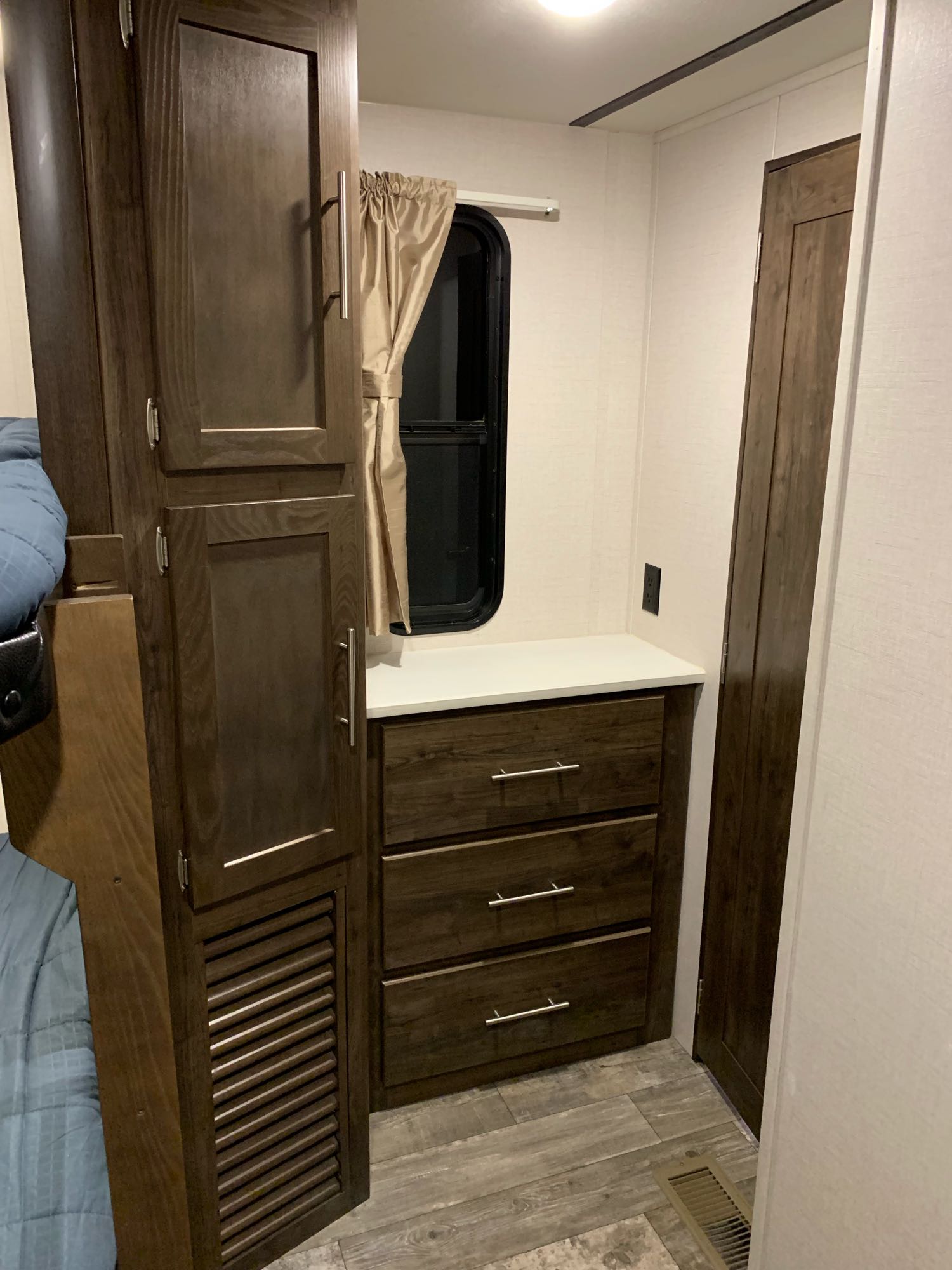RV rental interior: dark wood cabinets, dresser, bed, and window with curtain. Cozy and functional space.. keystone / Crossroads Volante 2019