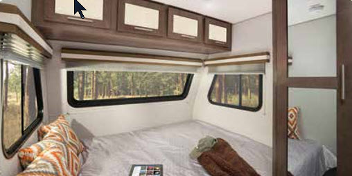 Cozy RV rental bedroom with a comfortable bed, overhead cabinets, and windows offering a forest view. Ideal for your next adventure.. Forest River Other 2019
