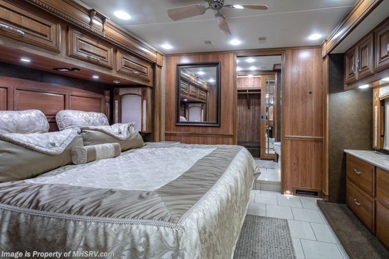 Inside a premium RV rental: a spacious bedroom with a comfy bed, rich wood cabinetry, ceiling fan & bath access.. Entegra Coach Anthem 44dlq 2016