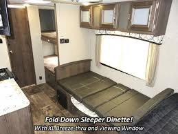This RV rental interior features a fold-down sleeper dinette, upper cabinets, large window, and bunk beds visible through a doorway.. Keystone RV Passport Express 2017