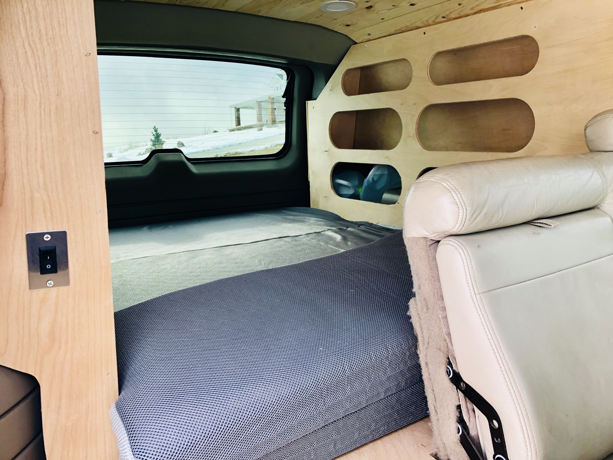 This rv rental shows a custom van interior with a comfy bed, integrated wood storage, and controls.. Chevrolet Suburban Overland 2001