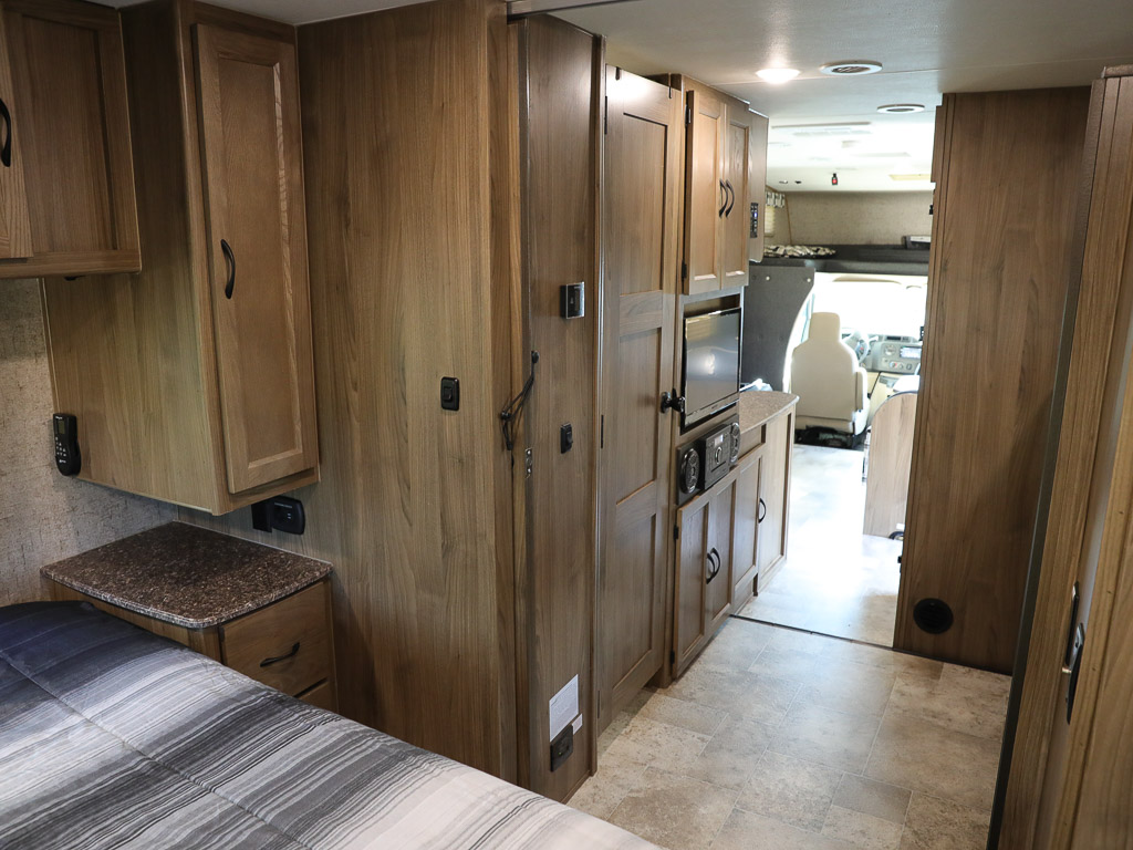 Spacious RV rental interior with wood cabinets, showing bedroom, kitchen, and cockpit ahead.. Ford Coachman 2018