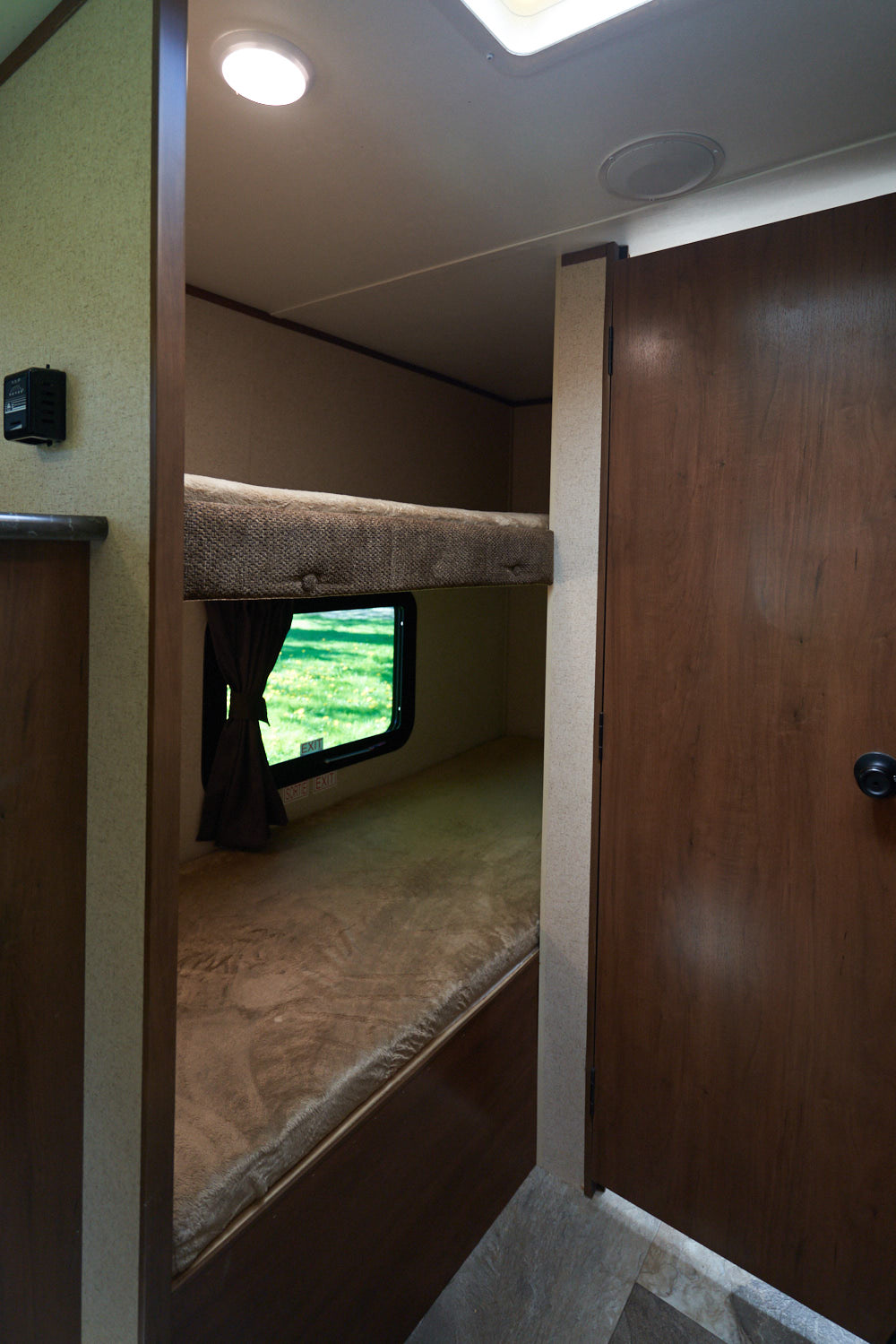 RV rental: Inside view of bunk beds with a window showing green outdoors. Features a bright ceiling light and a brown door.. Jayco Baja 154BH 2016
