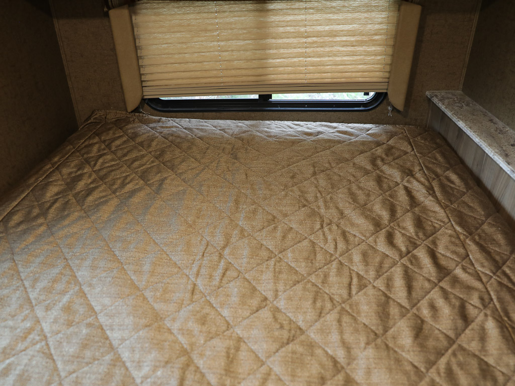 RV rental bedroom: A cozy space with a quilted comforter on the bed, a window with blinds, and a side shelf.. Coachmen Freelander 21RS 2016