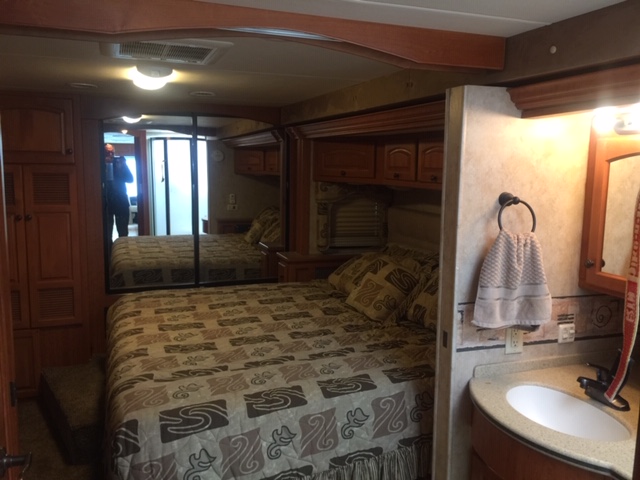 Spacious RV rental interior featuring a cozy bedroom with mirrored wardrobe and a convenient bathroom vanity. Perfect for travel.. Damon Tuscany 2008