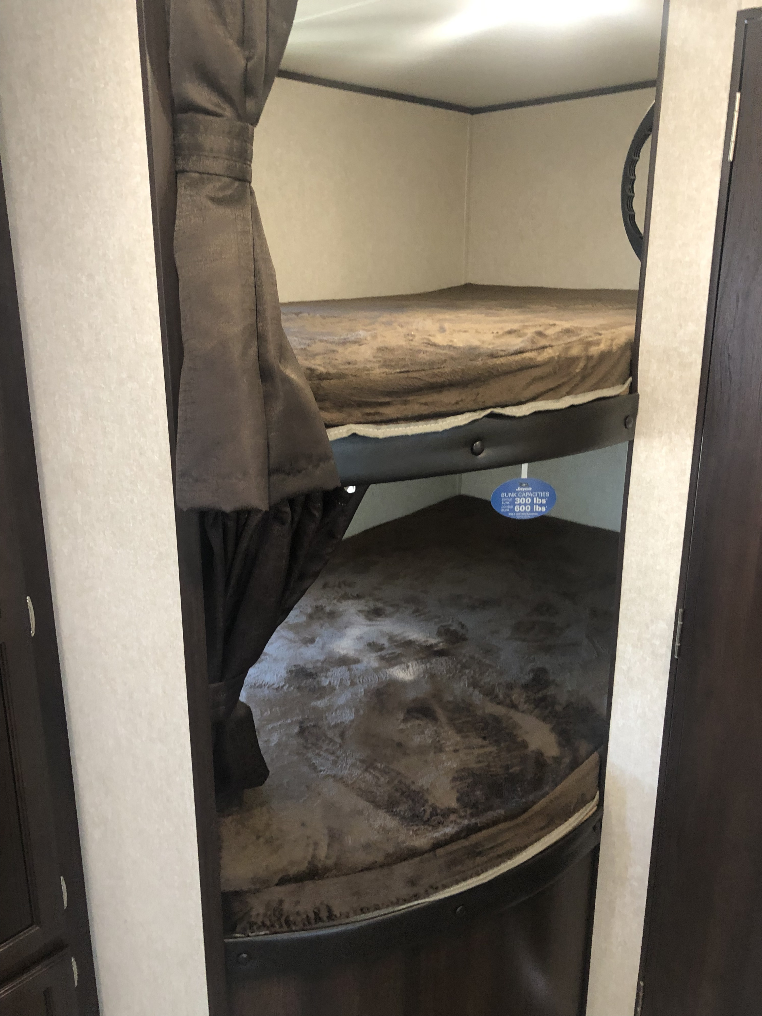 This RV rental features cozy bunk beds with privacy curtains and visible weight capacity labels, ideal for family travel.. Jayco Jay Flight 2019