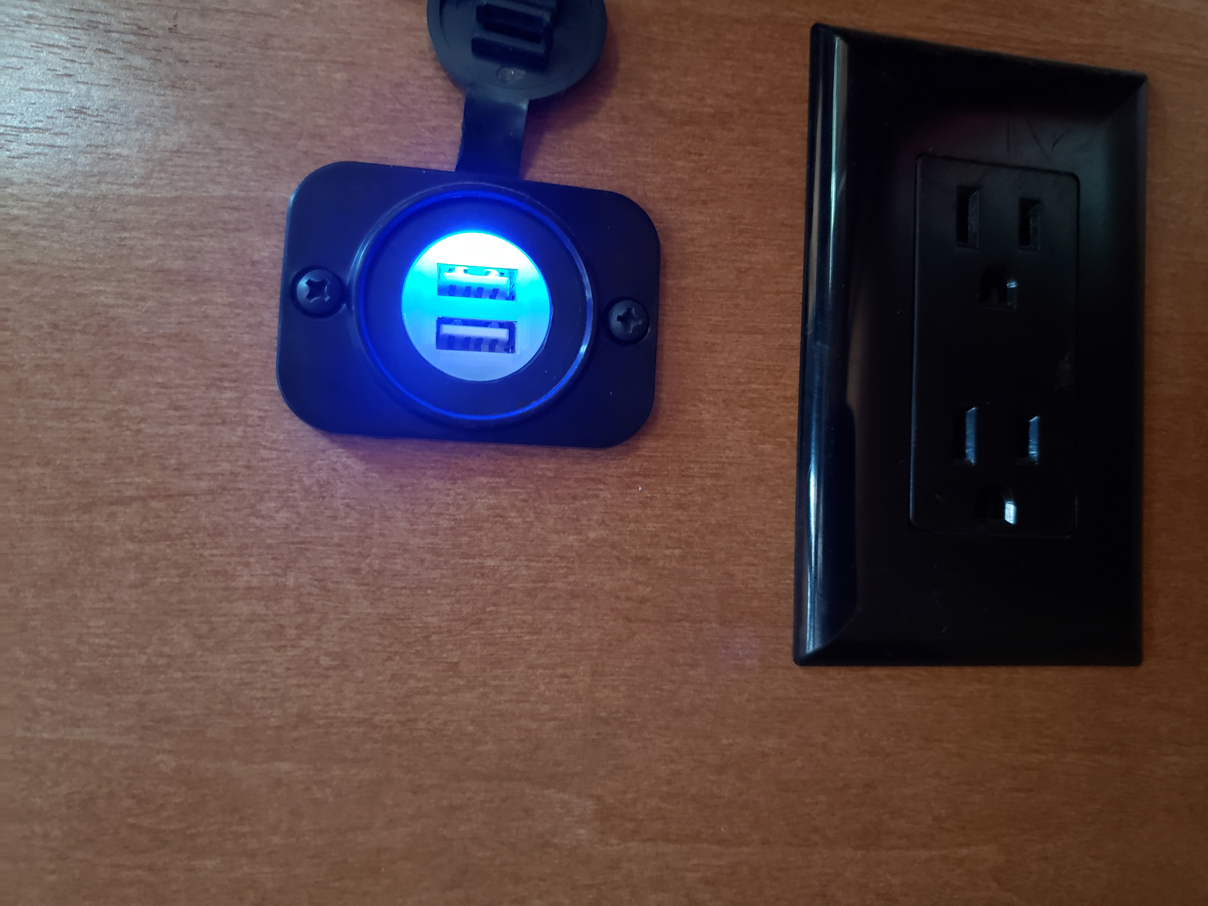 RV rental interior with glowing blue USB charging ports and a standard AC power outlet on a wood panel.. Winnebago Minnie Winnie 2018