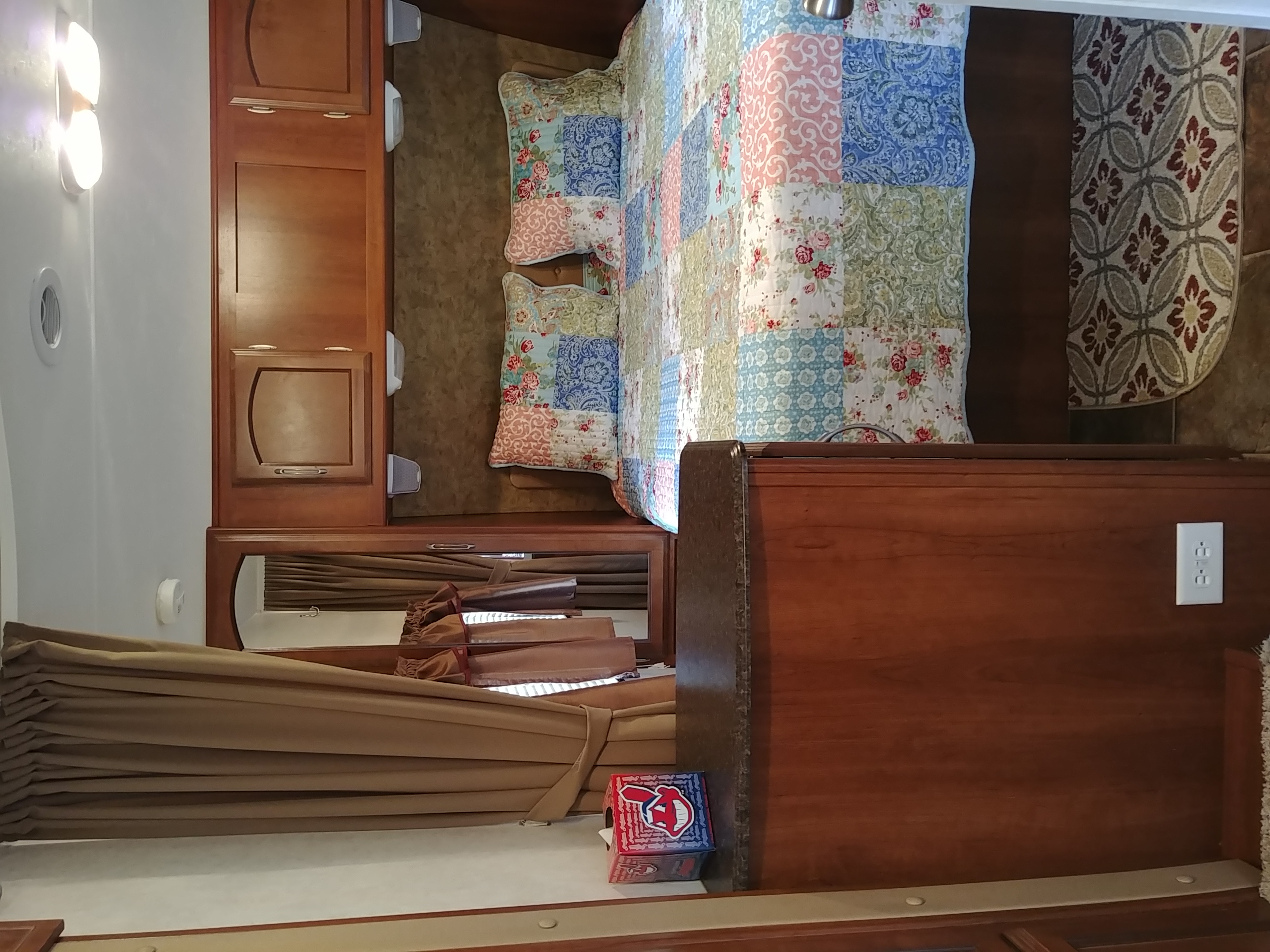 Cozy rv rental bedroom: patchwork bed, wood cabinets, window blinds. Compact and inviting space for travel.. Coachmen Freedom Express 2013