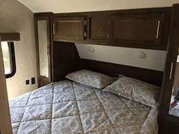 Comfortable RV rental bedroom featuring a cozy bed, overhead cabinets, and a window for scenic views during travel.. Forest River Cherokee Grey Wolf 2019