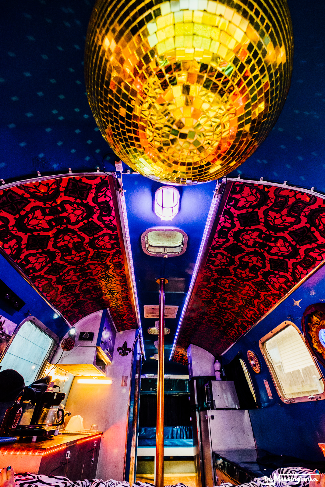 Experience a fun RV rental! This unique interior features a disco ball, party pole, and bright blue/red decor in a custom RV.. Airstream Argosy 1975