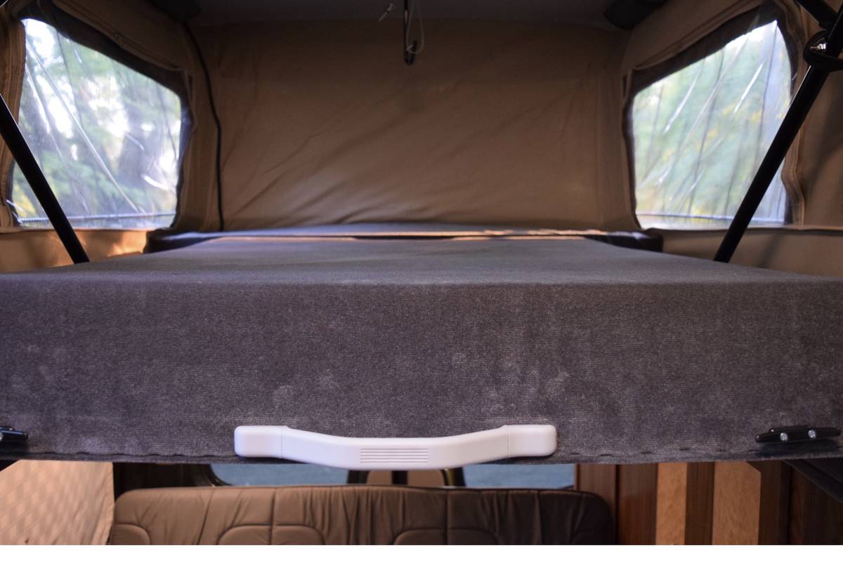 Elevated bed in this RV rental pop-top camper, with clear windows offering outdoor views.. Mercedes-Benz Sprinter 2016