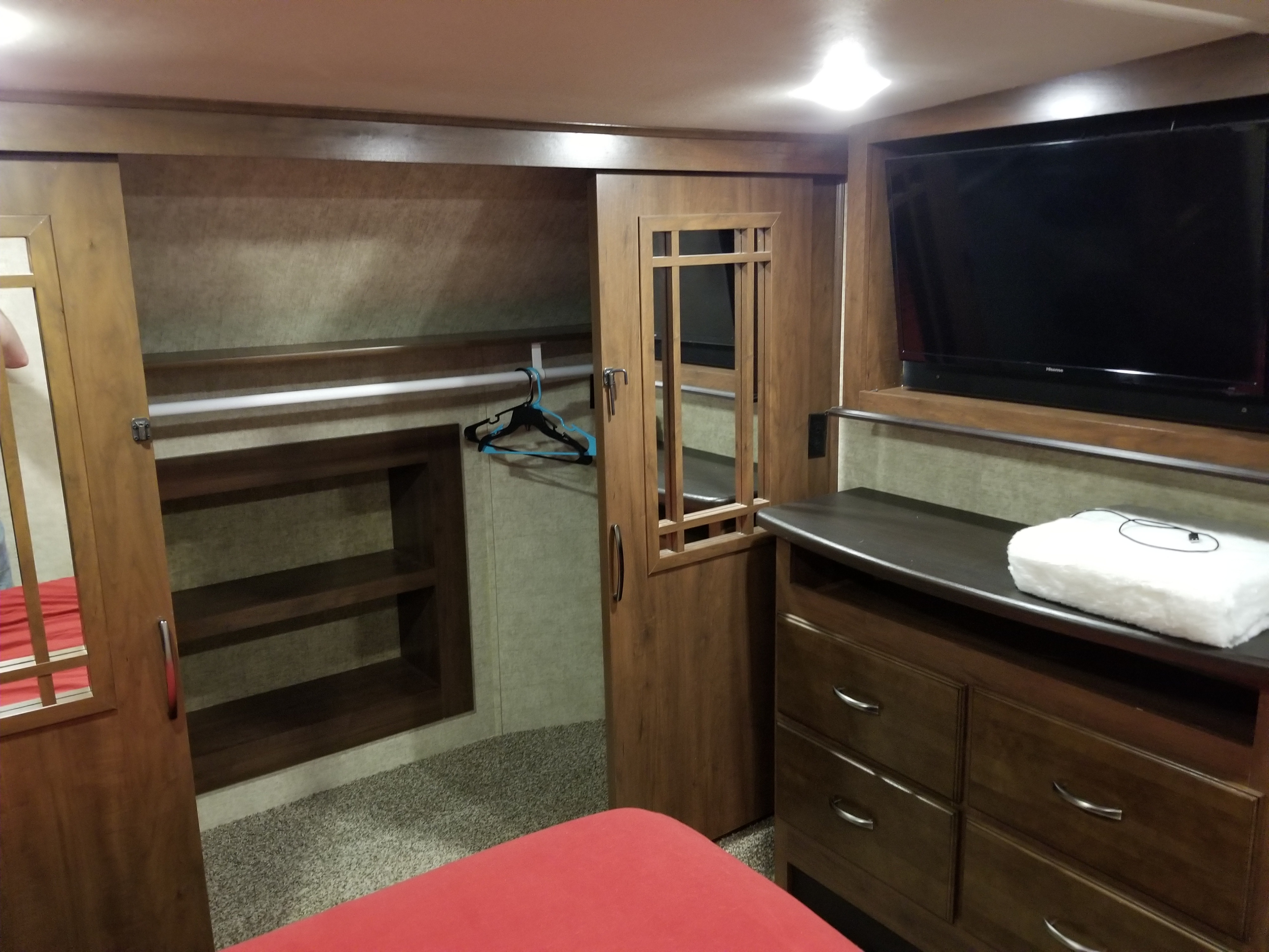 RV rental bedroom showcasing built-in storage: TV, dresser, and a closet with a hanging rod & shelves.. Forest River Sierra 2018