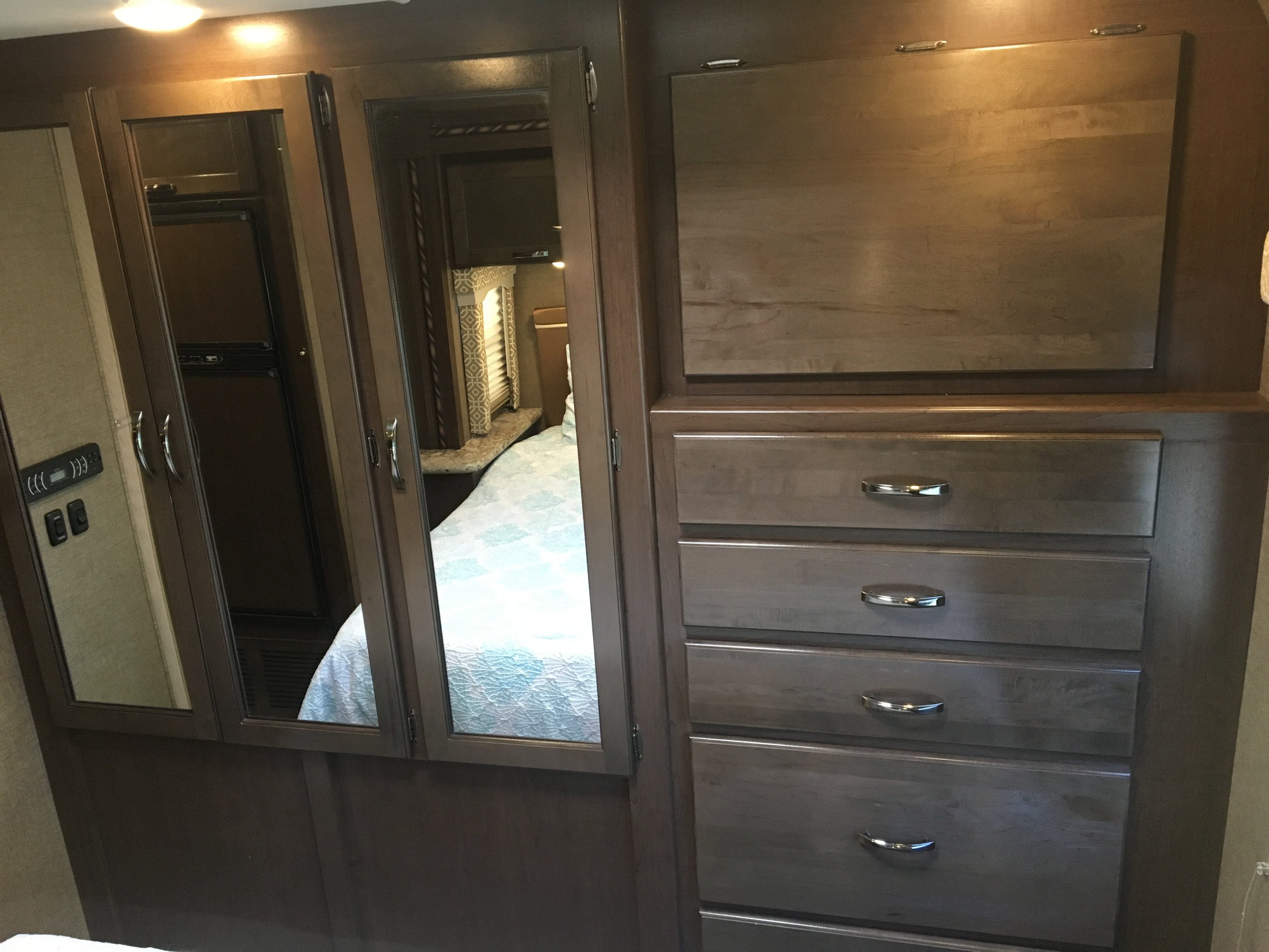 Explore this RV rental bedroom with mirrored closet doors, a fold-down table, and ample storage drawers. Efficient design.. Thor Freedom Elite 2017