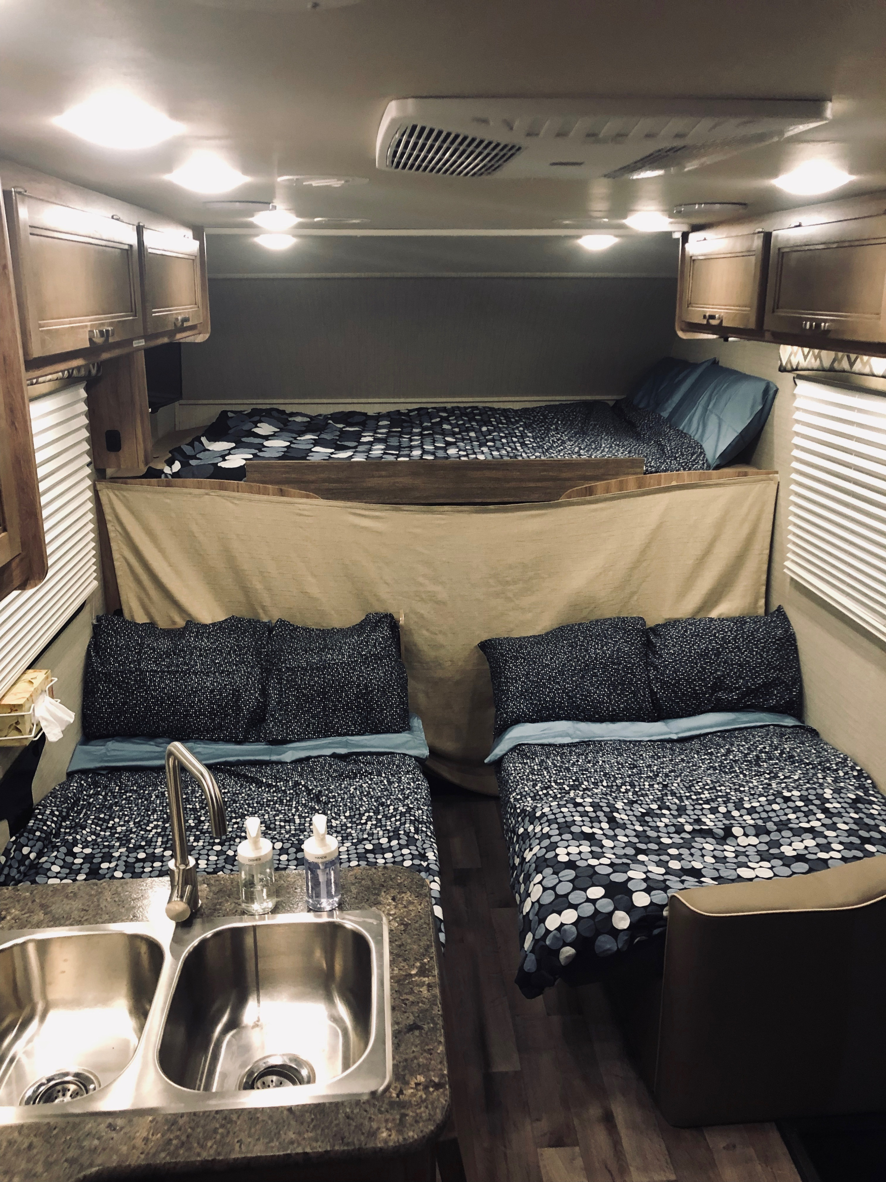 RV rental interior featuring comfortable bunk beds, a convenient sink, and overhead storage. Ideal for family travel.. Jayco Redhawk 2019