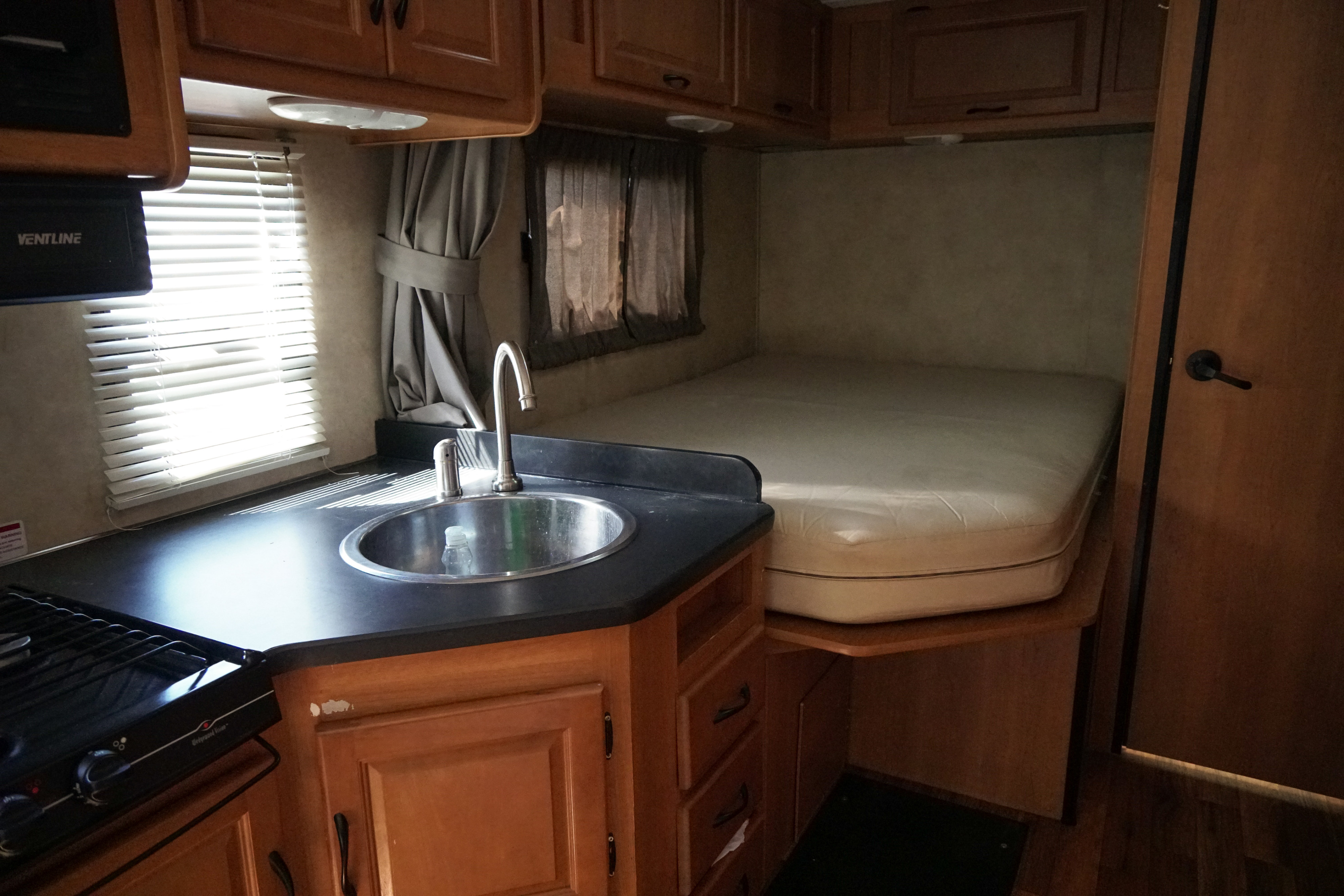 RV rental: Compact interior showing kitchen with sink/stove & built-in bed. Ideal for road trips.. Majestic Leisure Craft 23A 2014