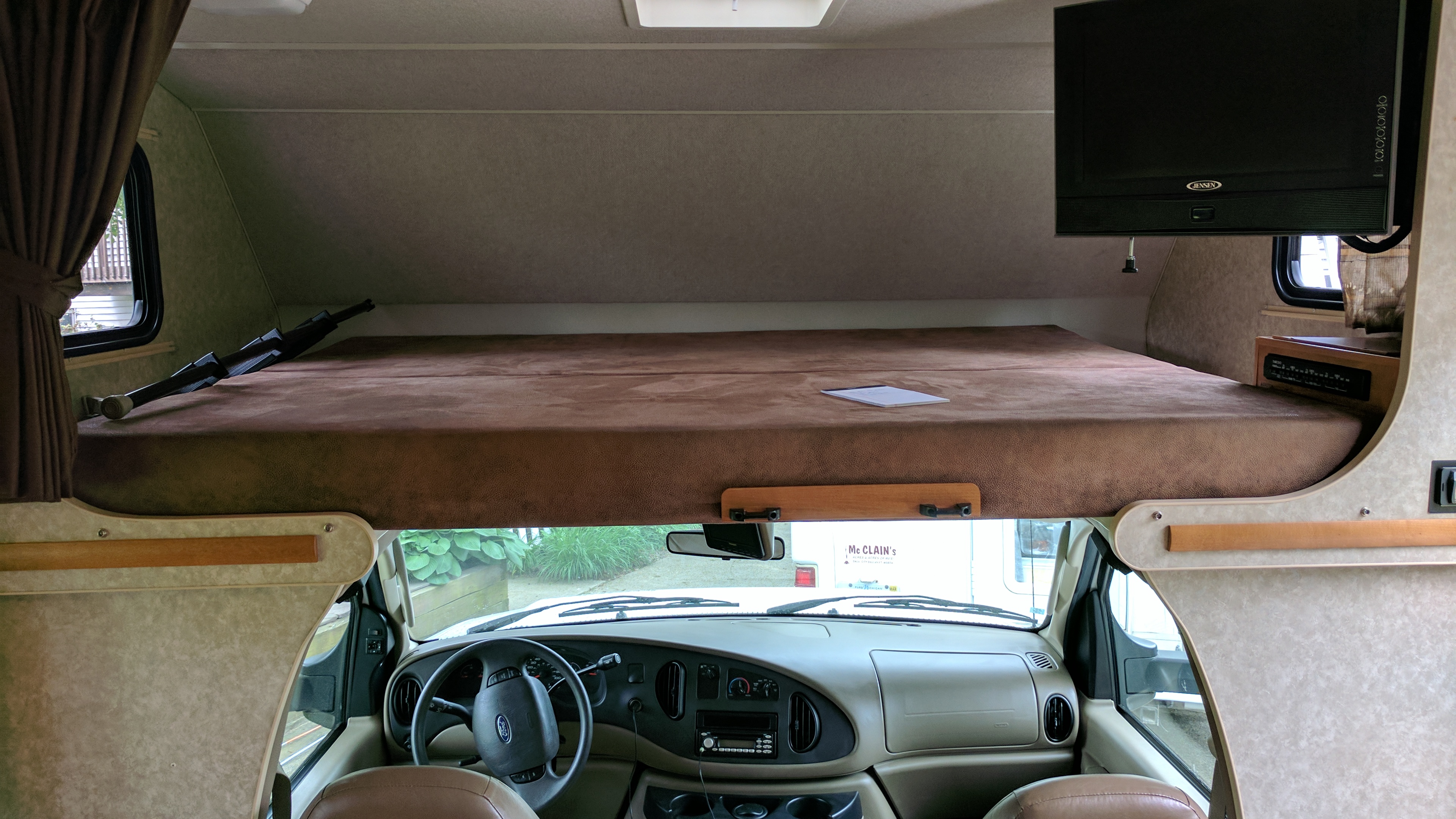Cozy RV rental interior showcasing a spacious cab-over bunk, driver's dashboard, and front window view.. Winnebago ITASCA 2009