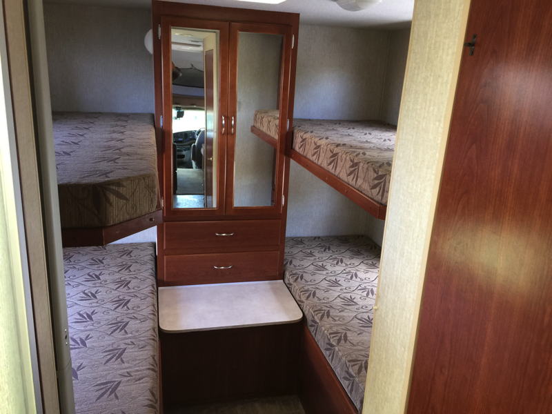 RV rental interior: four bunk beds (two on each side) surround a central cabinet with mirrored doors & drawers.. Fleetwood Tioga 2008