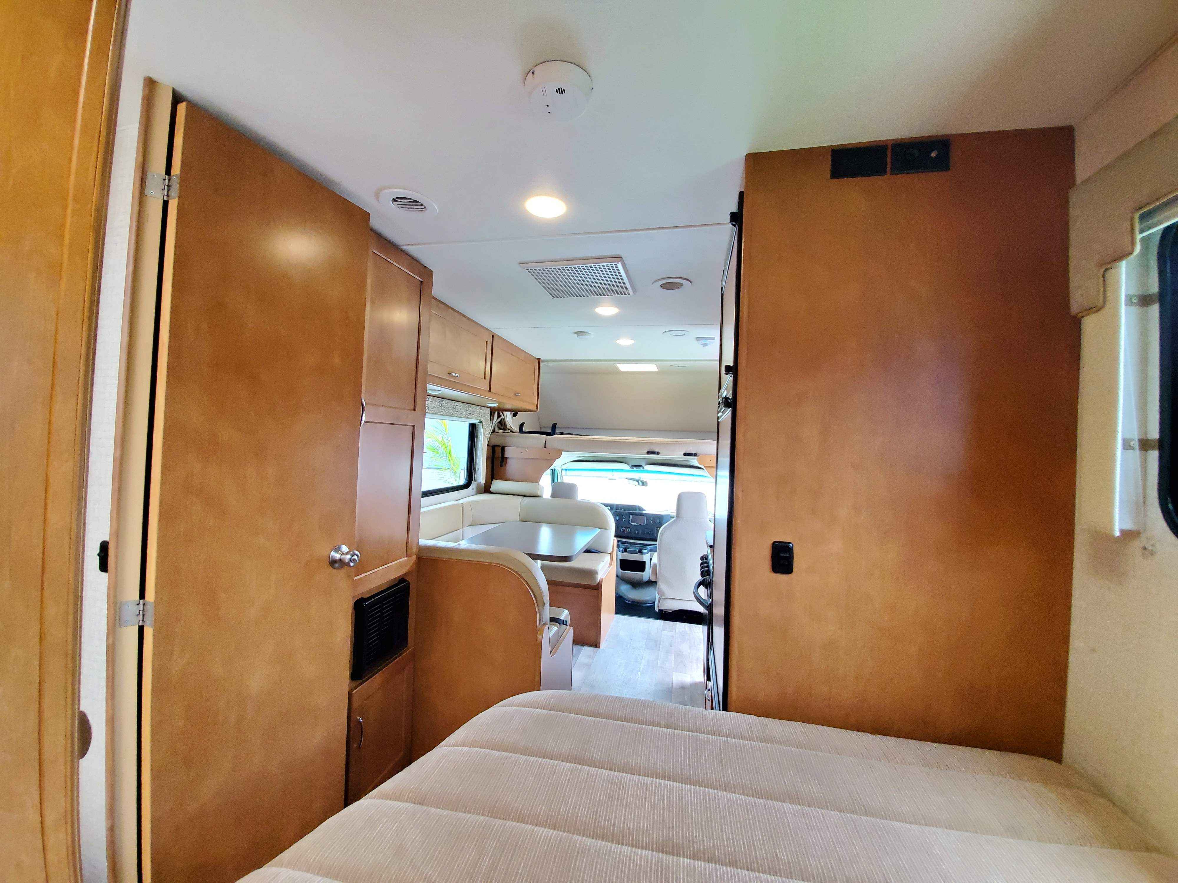 Spacious RV rental interior from bedroom perspective, revealing dining booth and driver's cab. Ideal for road trips.. Winnebago Minnie Winnie 2018