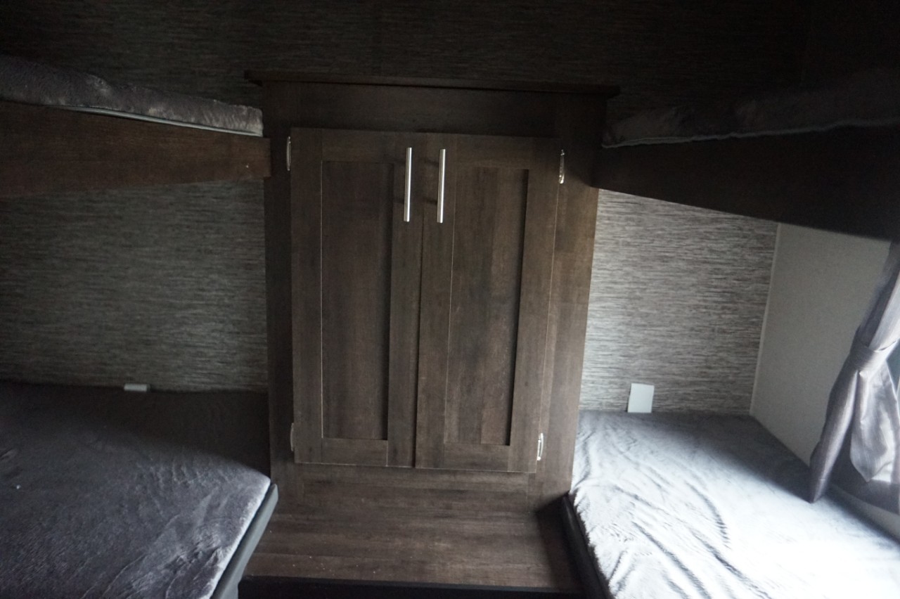 Cozy RV rental bunk beds, four in total, flanking a central storage cabinet. Ideal for family adventures.. K-Z Manufacturing sportsmen 301bhse 2020