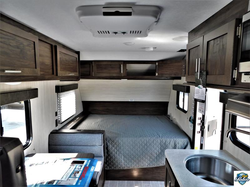 Inside this RV rental, a compact yet functional interior features a cozy bed, kitchen sink, and ample overhead storage for travel.. Forest River Cherokee Wolf Pup 2019