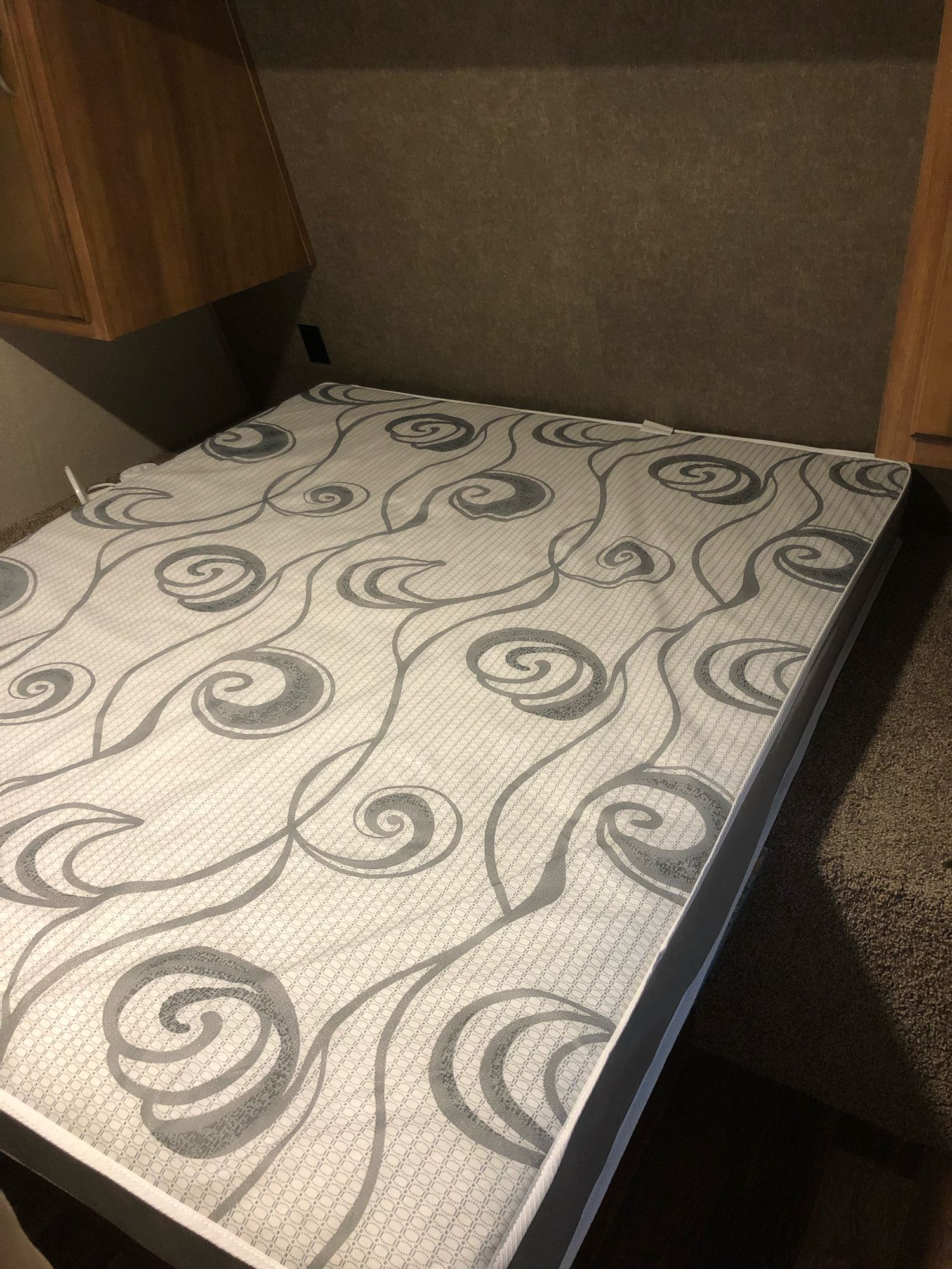 RV rental: Detailed view of a bedroom interior featuring a patterned mattress and wood cabinets. The room has textured walls and carpet.. Keystone Springdale 2018