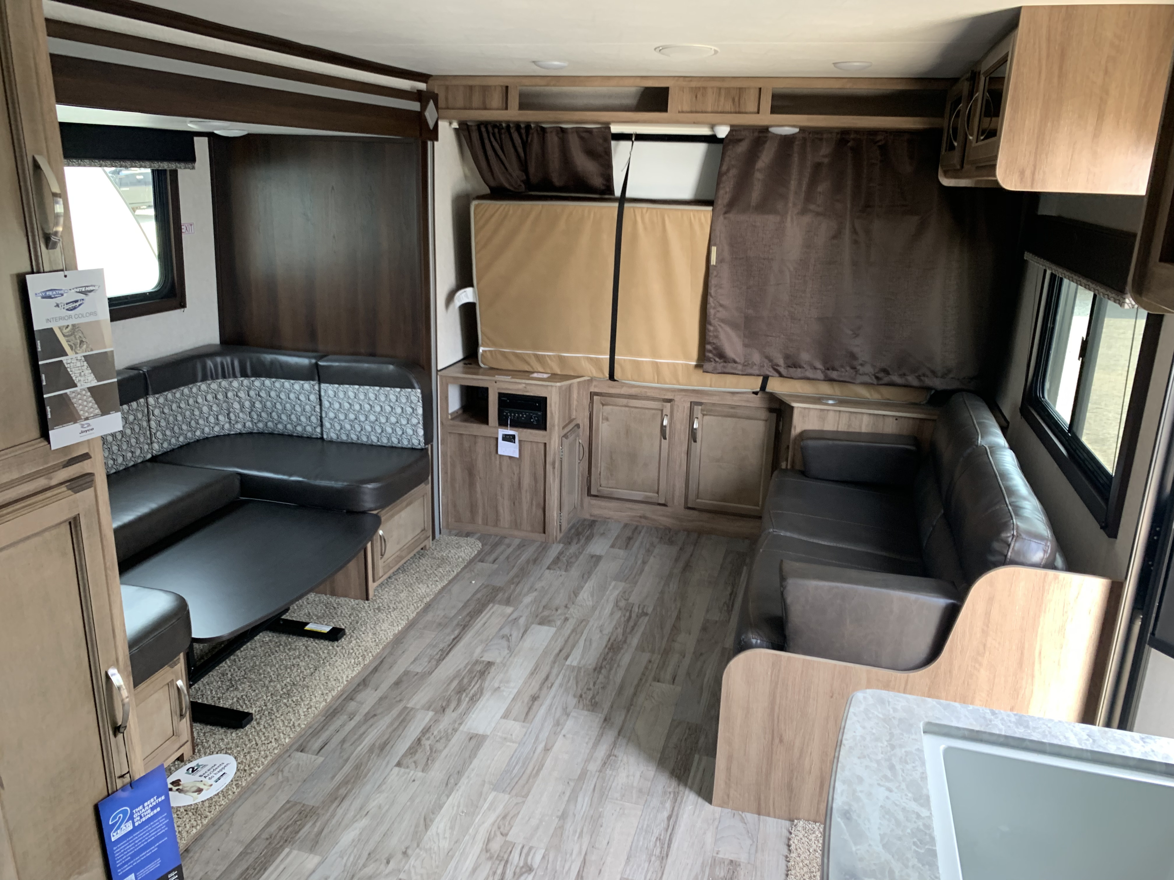 Spacious RV rental interior featuring a comfortable U-shaped dinette, separate sofa, and wood-look flooring.. Jayco Jay Feather 2019