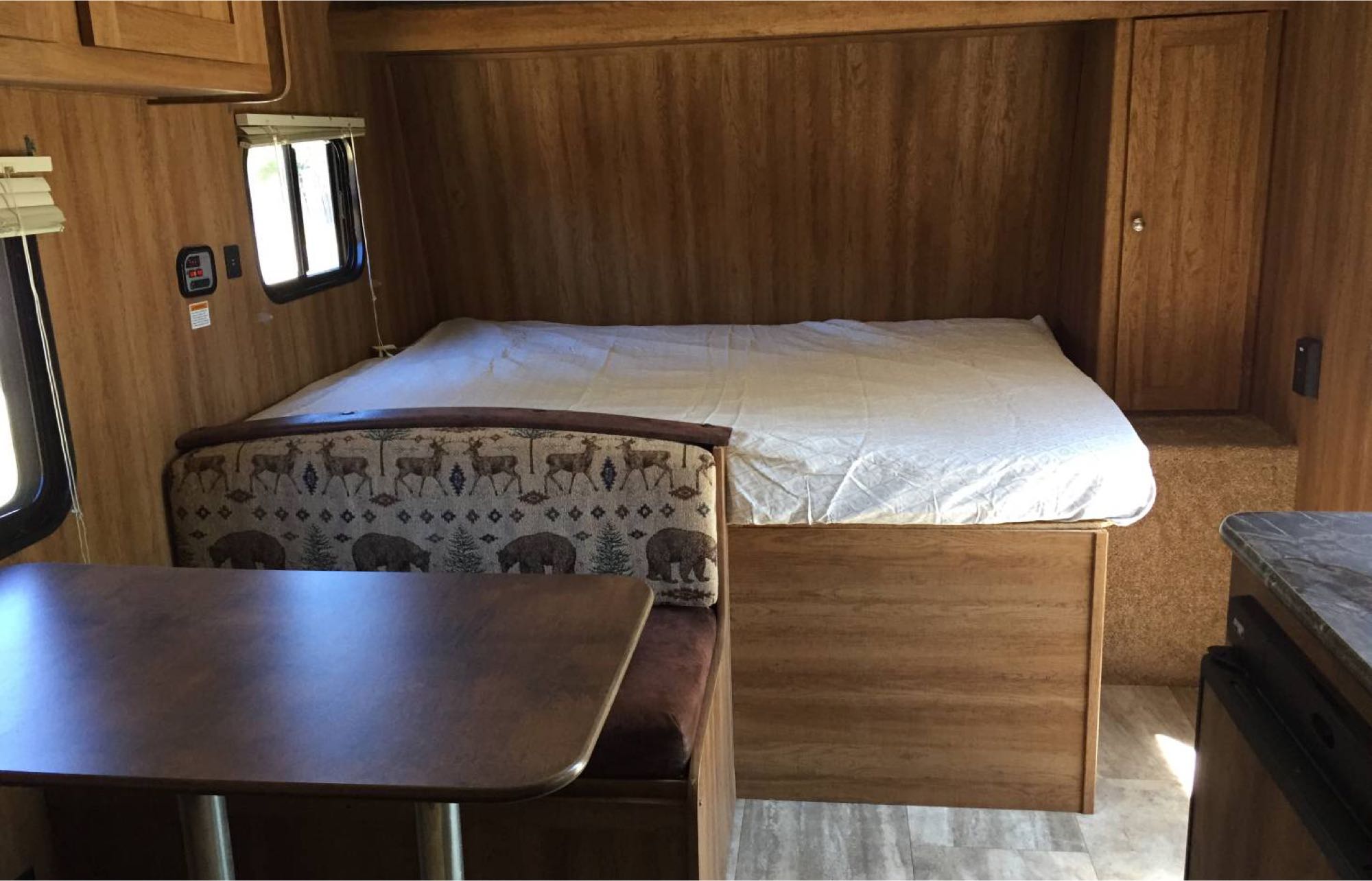 Explore this RV rental's interior featuring a comfortable bed, a dinette with charming wildlife patterns, and warm wood accents.. Keystone Hideout 2016