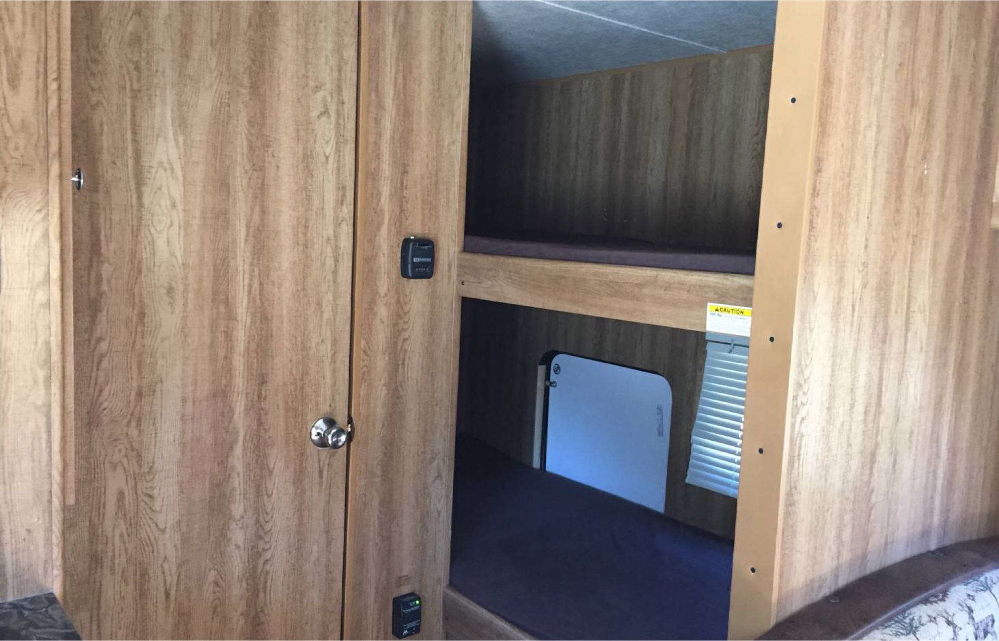 Cozy bunk beds in an RV rental, featuring wood paneling, a window, and comfortable mattresses, ideal for family trips.. Keystone Hideout 2016