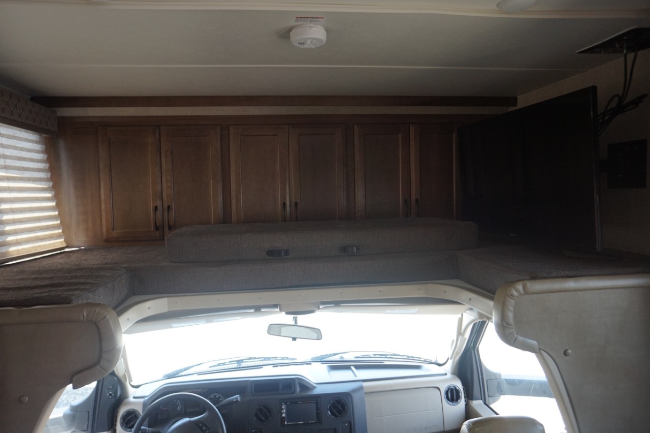 RV rental interior view: front cab, cozy overhead bunk bed with cushions, ample storage cabinets, and a mounted TV.. Gulf Stream conquest 2020