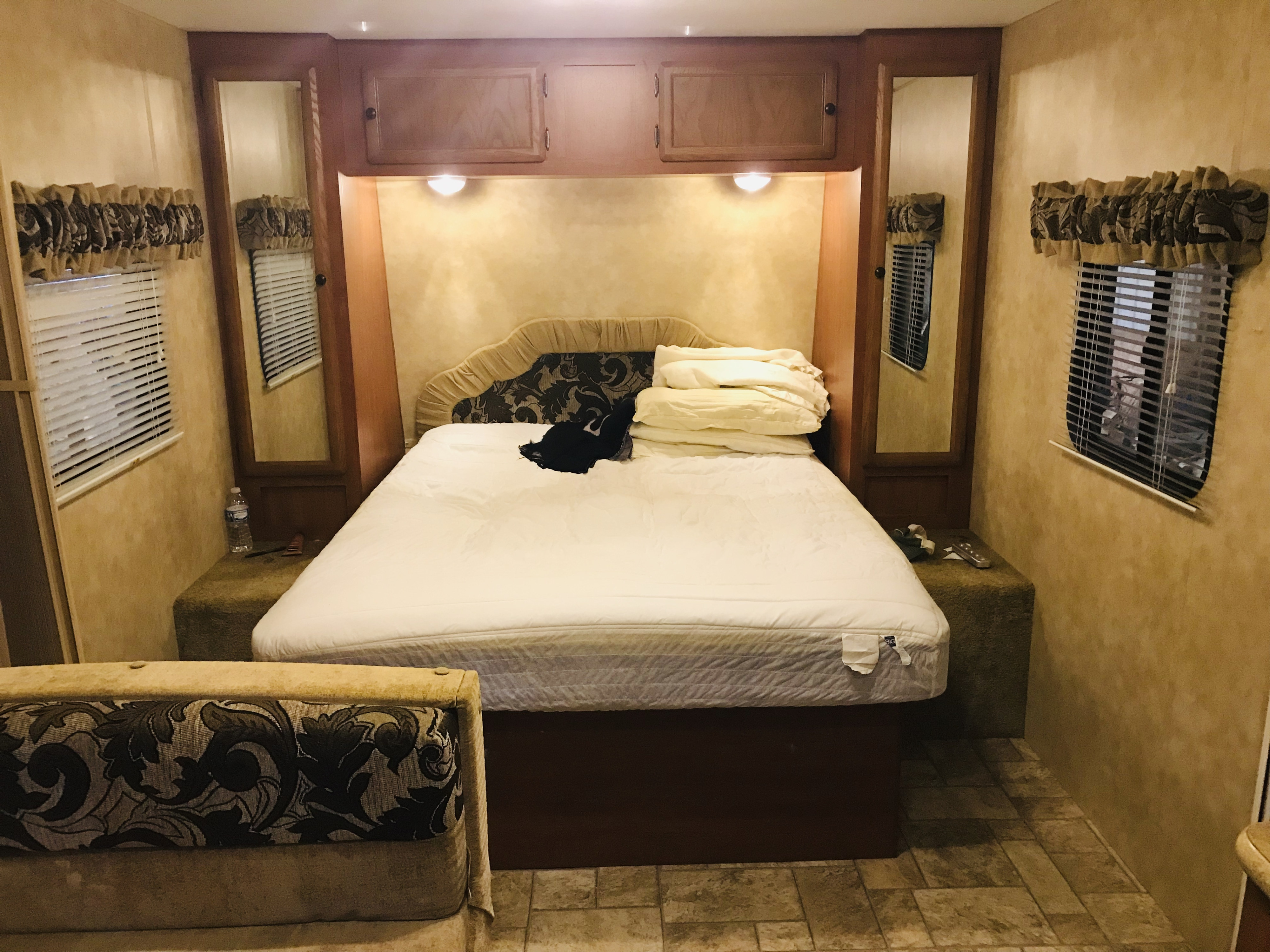 This inviting RV rental bedroom features a cozy bed, ample overhead storage, and mirrored closets for a comfortable stay.. K-Z Manufacturing Sportsmen 2011
