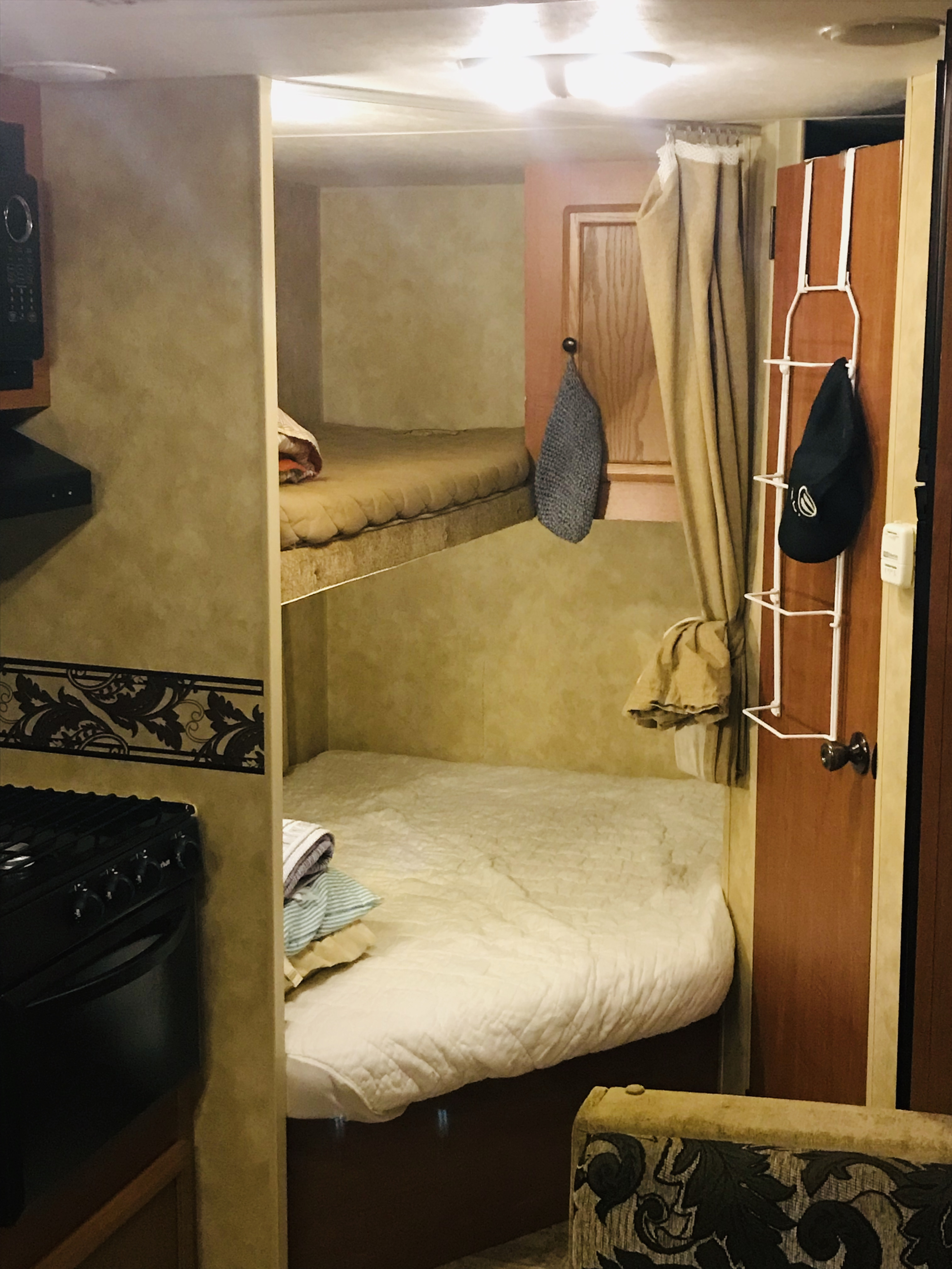 An RV rental interior features bunk beds, a compact kitchen with a stovetop, and a door with an over-door organizer.. K-Z Manufacturing Sportsmen 2011