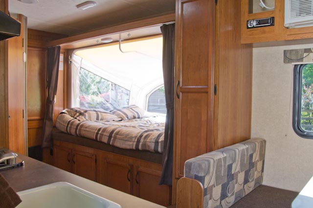 This RV rental interior features a cozy pop-out bed, patterned seating area, and compact kitchen. Ideal for road trips.. Starcraft Launch Extreme Hybrid 2015