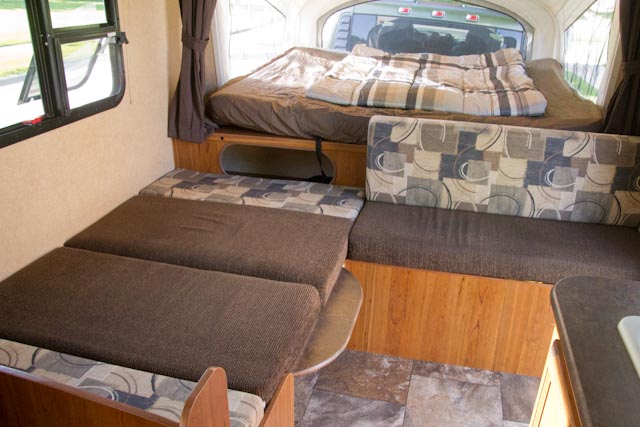 Pop-up RV rental interior: a comfy bed, a dinette with patterned cushions, and a side window, ideal for travel.. Starcraft Launch Extreme Hybrid 2015