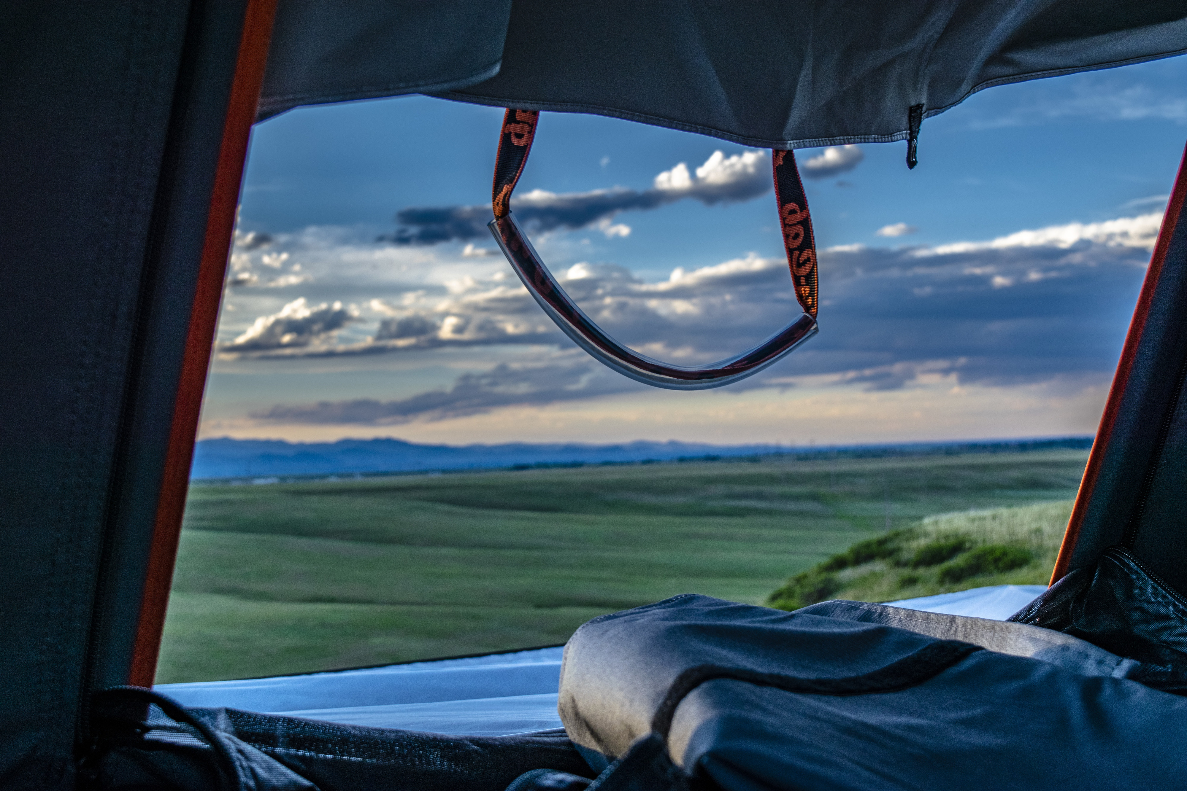 Camping with an RV rental! Inside a rooftop tent, enjoy panoramic views of green fields, distant mountains, and a cloud-filled sky.. Toyota 4Runner 2022