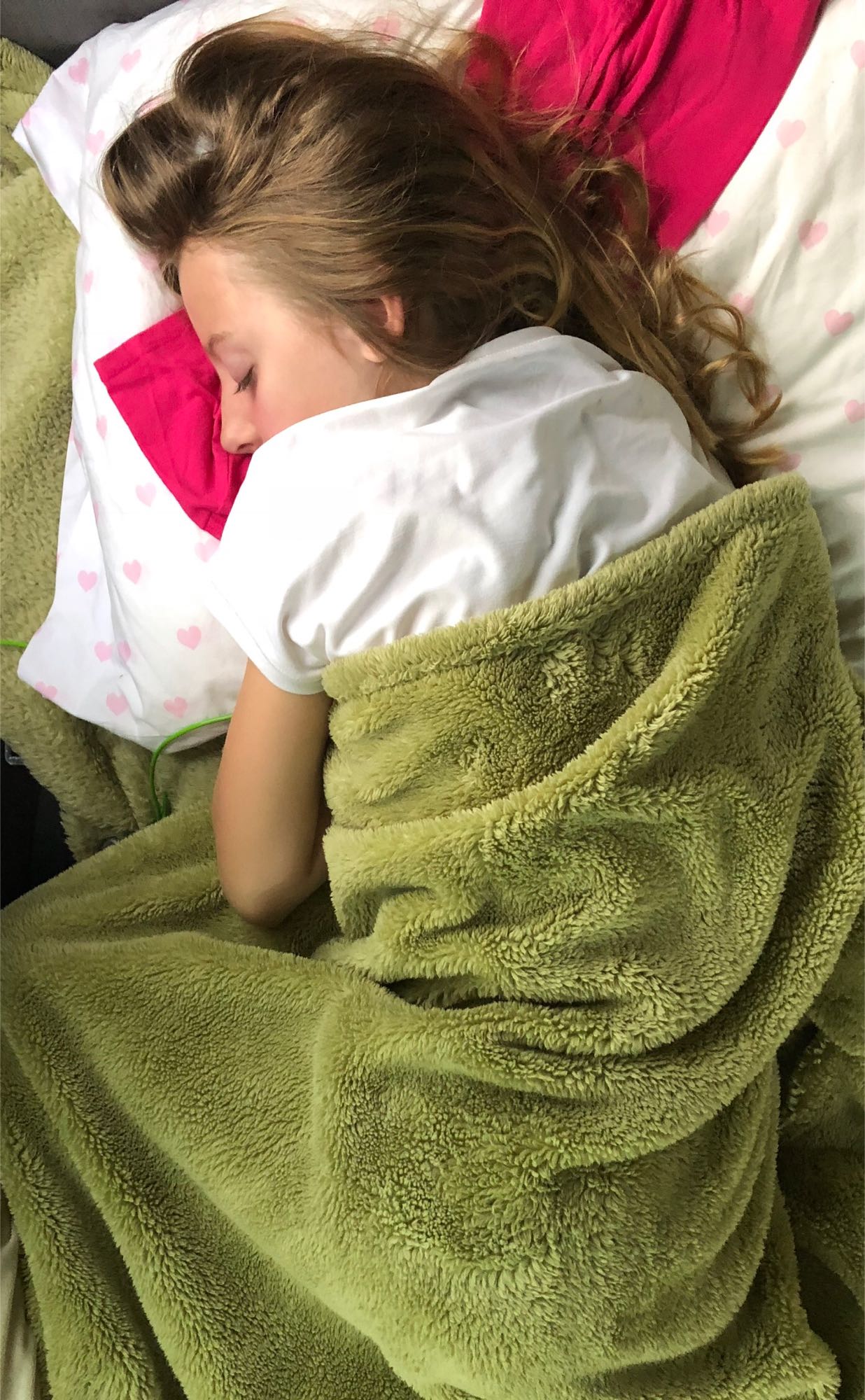 Relaxing sleep in an RV rental. A young person is comfortably tucked under a soft green blanket and heart pillow.. mercedes Sprinter 170 4wd 2016