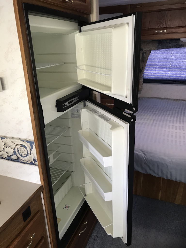 An empty, clean two-door RV refrigerator, with wire shelves and door bins, seen from the open door. Ideal for your rv rental.. Dutchmen Express 2006