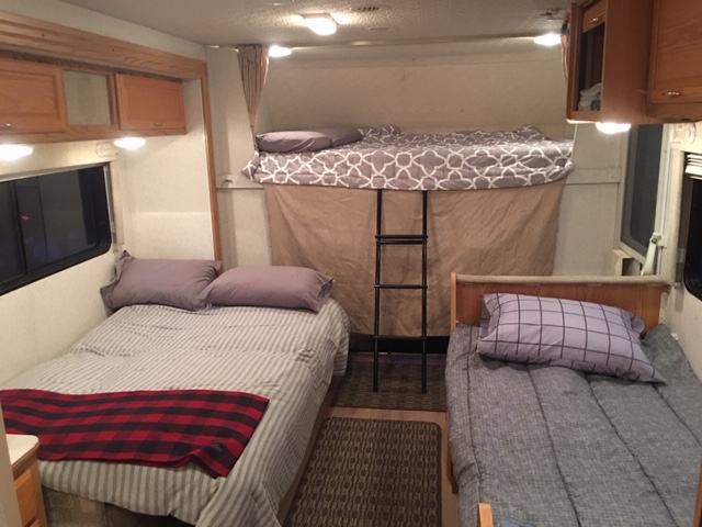 RV rental interior shows a main bed, a side bed, and a top bunk with ladder, offering multiple sleeping options.. Winnebago Minnie 2002