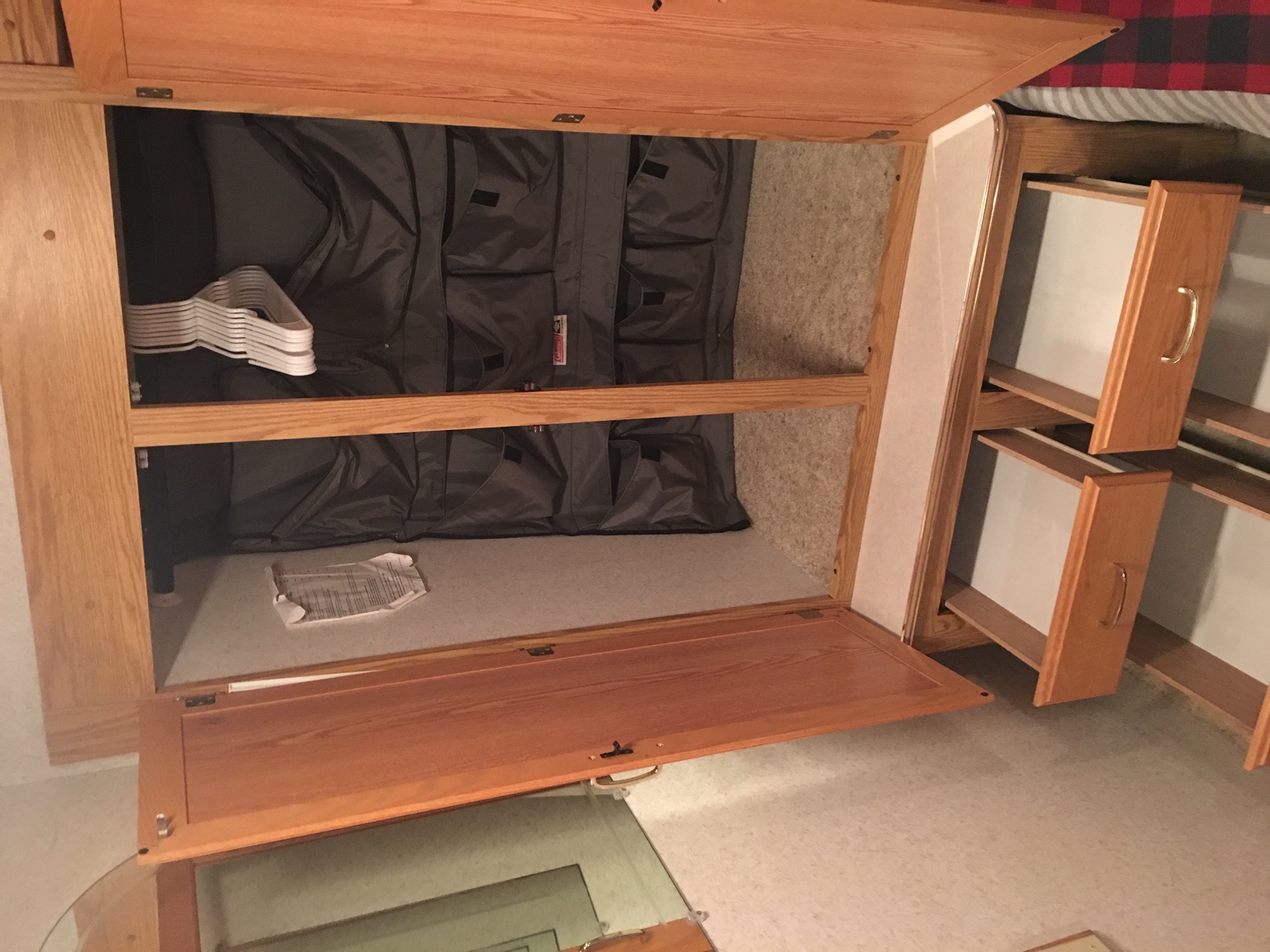 Smart RV rental storage: open wooden wardrobe with gray fabric organizer, hangers, & accessible drawers visible.. Winnebago Minnie 2002