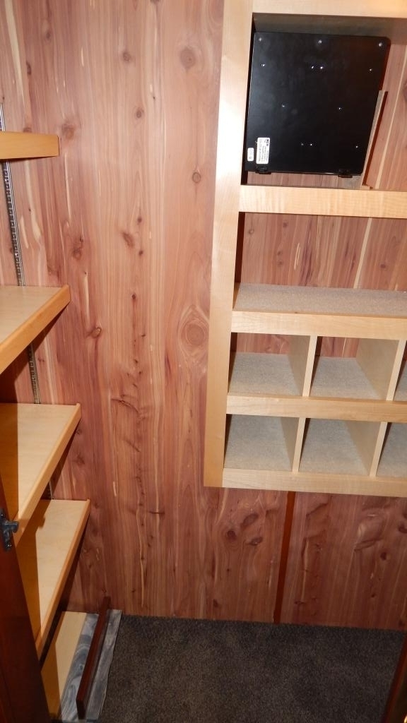Inside this RV rental cedar-lined closet: adjustable wood shelves, shoe cubbies, and a wall-mounted black unit.. Newmar Essex 2018