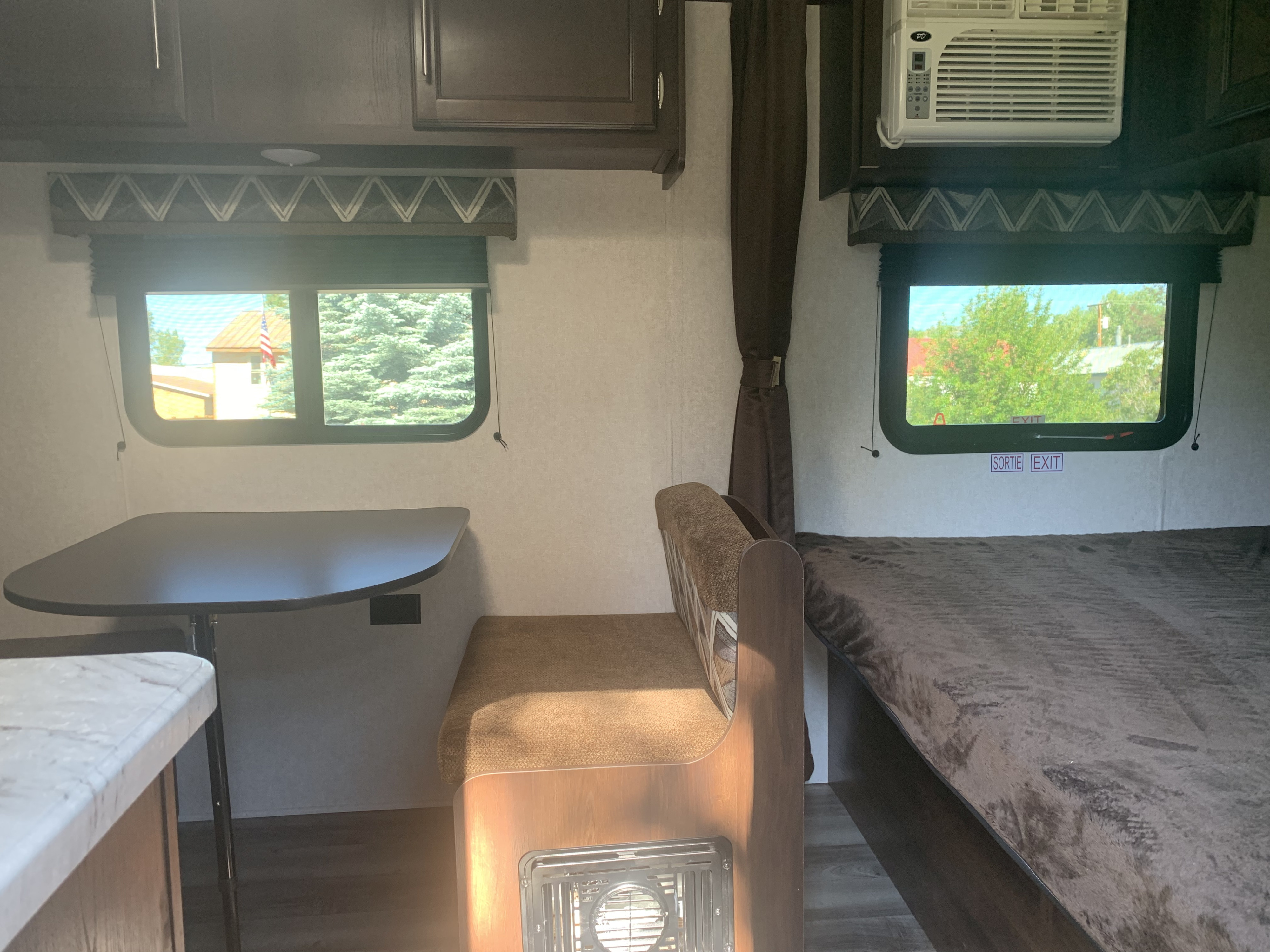 Experience comfort in this RV rental. Interior shows a dinette on the left and a bed on the right, with windows offering views.. Jayco Jay Flight SLX 174BH BAJA 2019