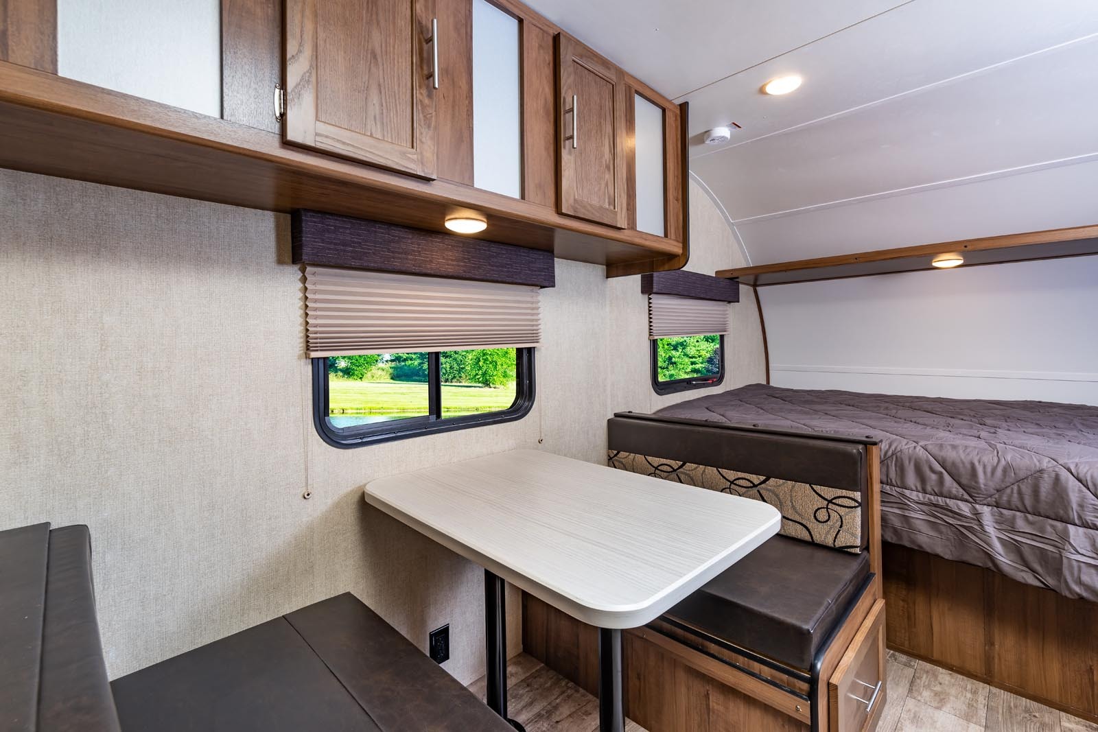 Cozy RV rental interior featuring a dinette, table, and bed, with windows showcasing a serene outdoor view.. Gulf Stream 199DD 2020