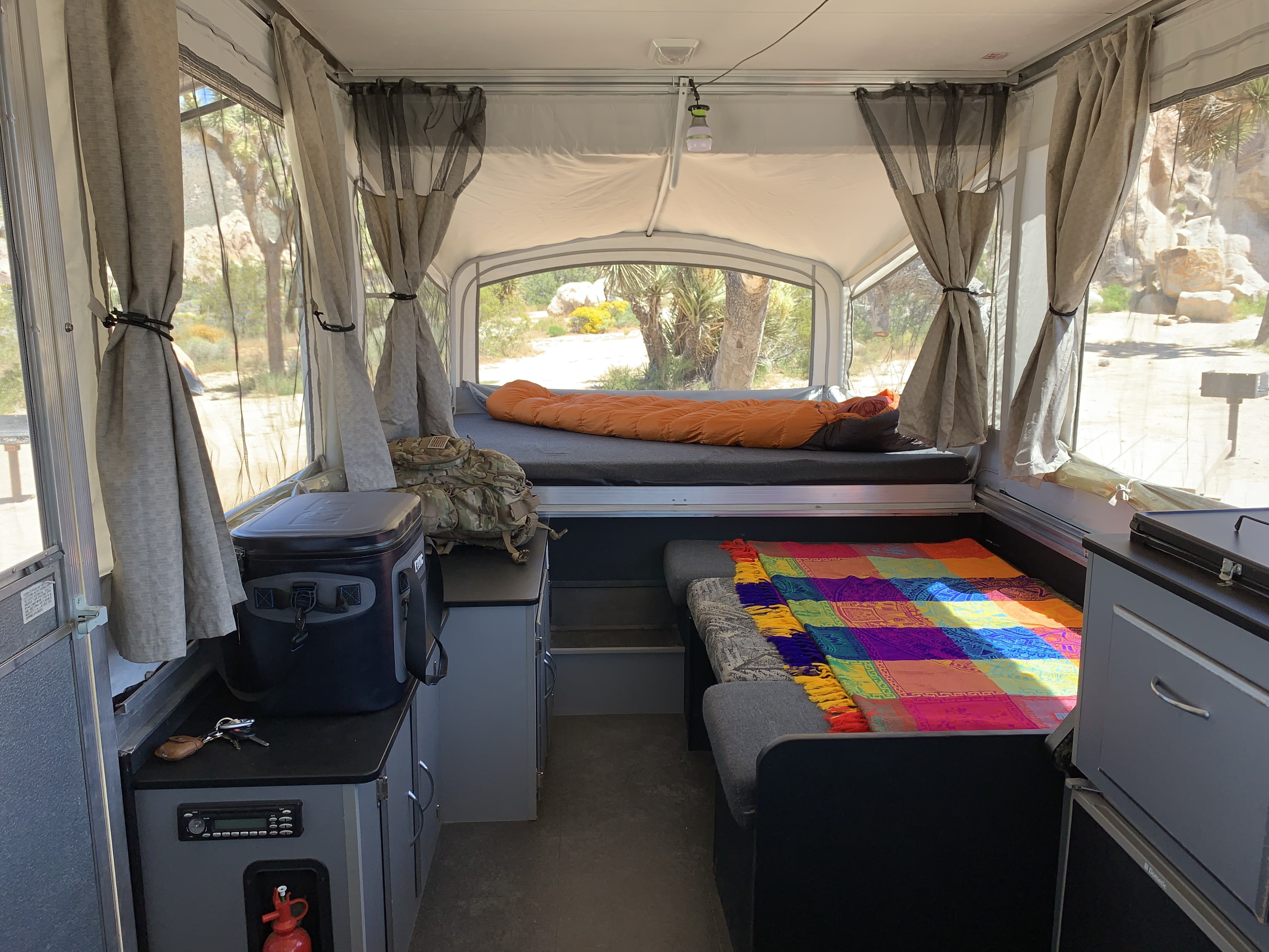 Cozy pop-up RV rental interior with a comfy bed, colorful blanket, and desert landscape views. Ideal for camping.. Fleetwood Evolution 1 (E1) 2008