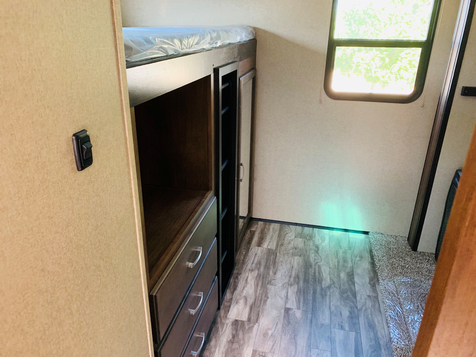 RV rental interior with cozy bunk beds, built-in storage, bright window, and wood-look flooring.. Grand Design Reflection 2019